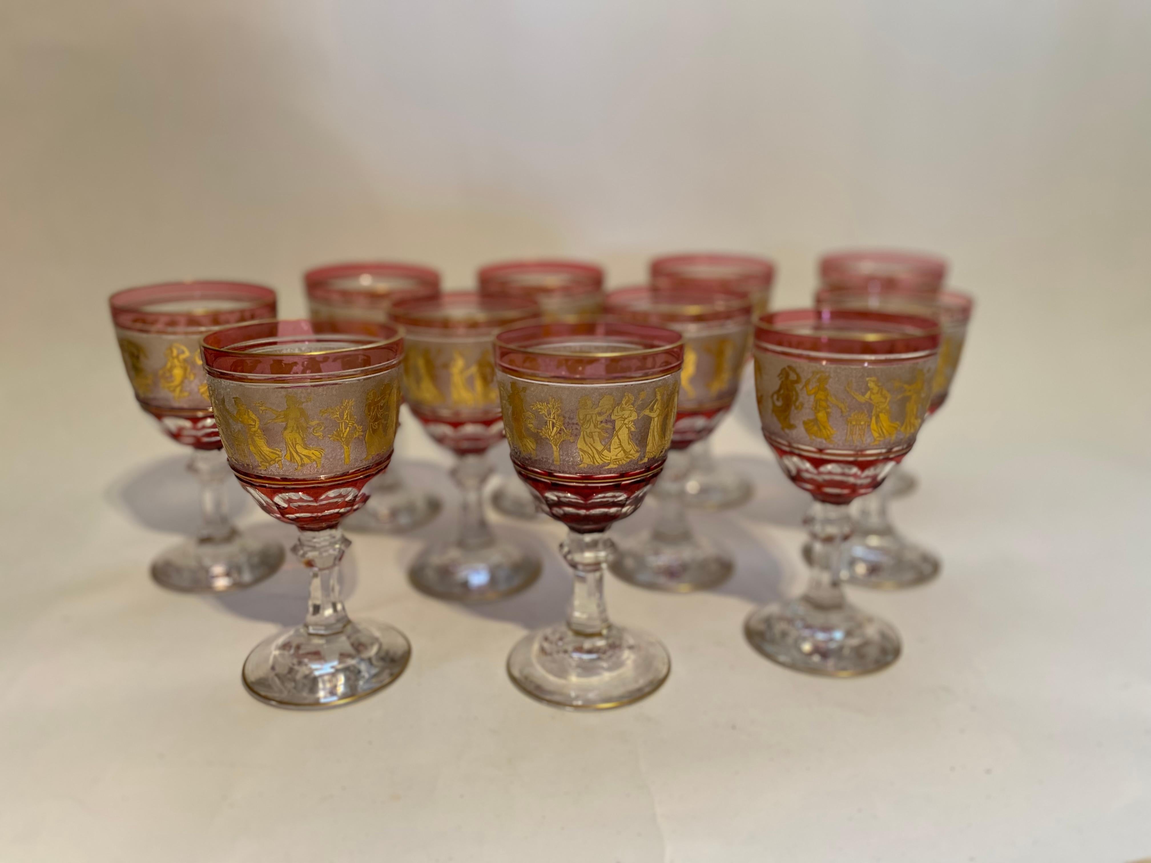 A gorgeous elegant set of 11 heavy blown and ruby cased crystal goblets by the re known firm of Val Saint Lambert. One of their signature patterns, these lovely pieces feature Greco Roman 24 Karat Gilt Figures on an acid cut back ground and are
