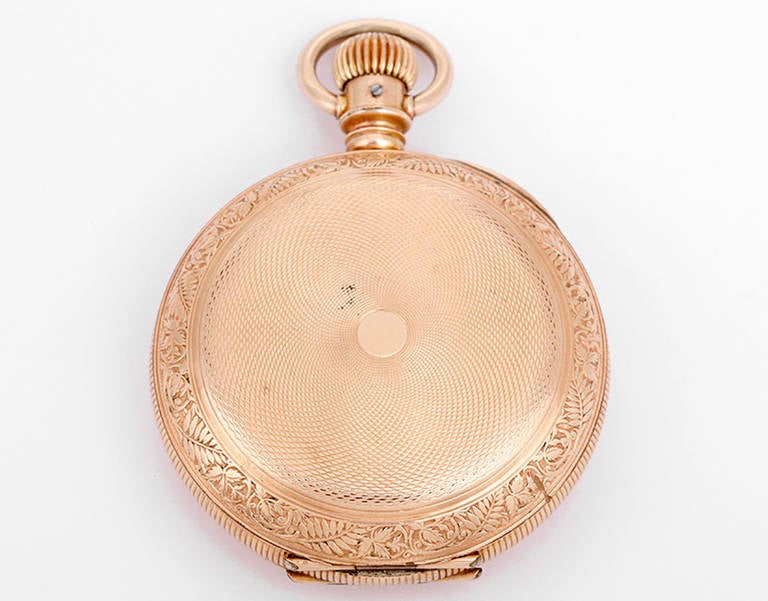 Manual-wind movement, 18 size, Grade 102, Model 2. Gold-filled case with coin edge band, 54mm diameter. Front and back of case are intricately engraved with a floral botanical design around the engine-turned design in the center. White enamel dial