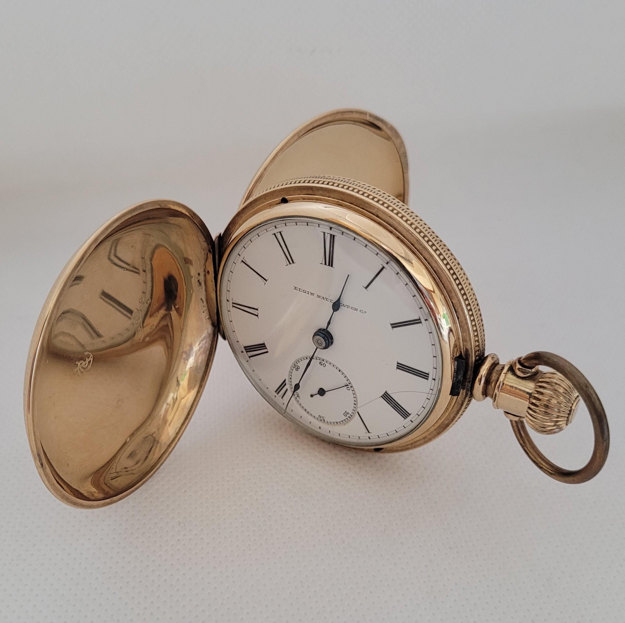 Gold-plated Elgin National Watch Co. 53mm pocket watch, white face, black Roman numerals that has been fully cleaned and serviced and includes a 90-day warranty. The face of the watch has a hairline crack. The case is stamped: Newport caste 982750