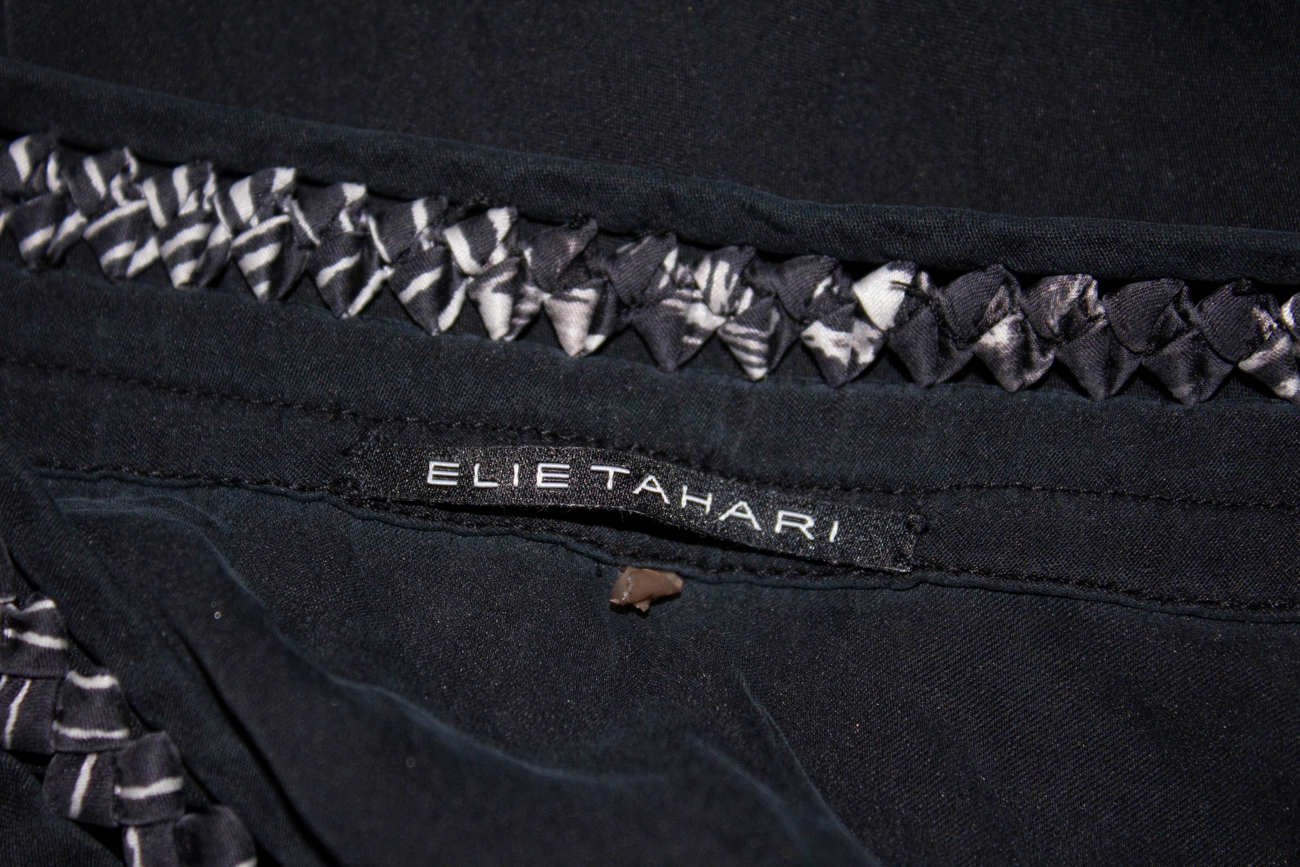 A super soft silk top by Elie Tahari. In black silk the top has detail at the neckline, pintucks, a popper front opening and elastic cuffs. Measurements Bust up to 38'', length 39''