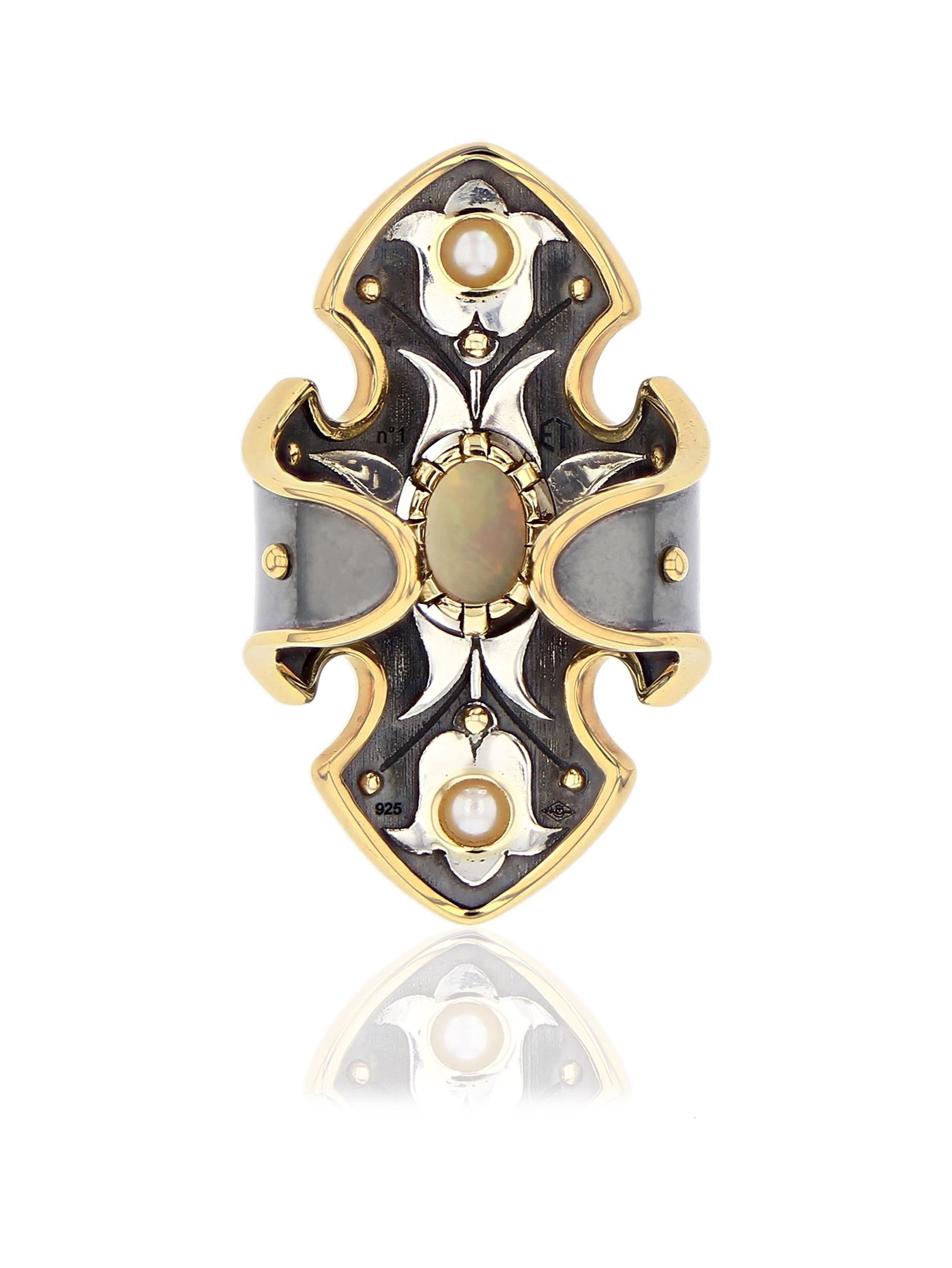 Bague Bouclier Opale Or Jaune Diamants

Patined silver shield-shaped ring rail whose contours and claws are in yellow gold. It is set with an opal encercled with diamond in its center, 12 gold spikes, 2 topazes and 2 Akoya pearls. Inside the ring is