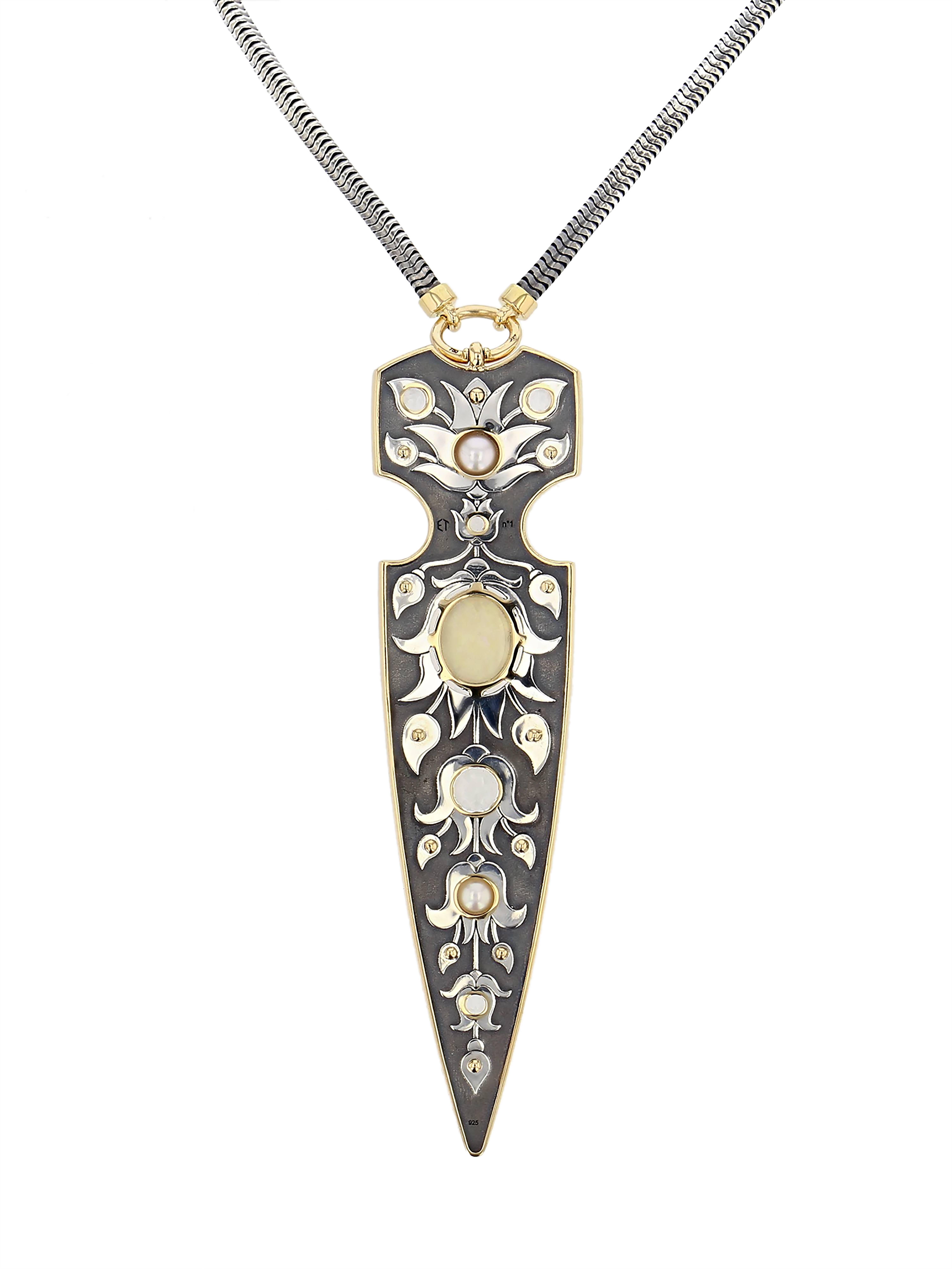 Pendentif Dague Opale Or Jaune Diamants

Dagger necklace mounted on a patinated silver chain with a pendant whose contours and claws are in yellow gold. The dagger is set with 12 yellow gold spikes, a variation of 5 topazes, 2 Akoya pearls and an
