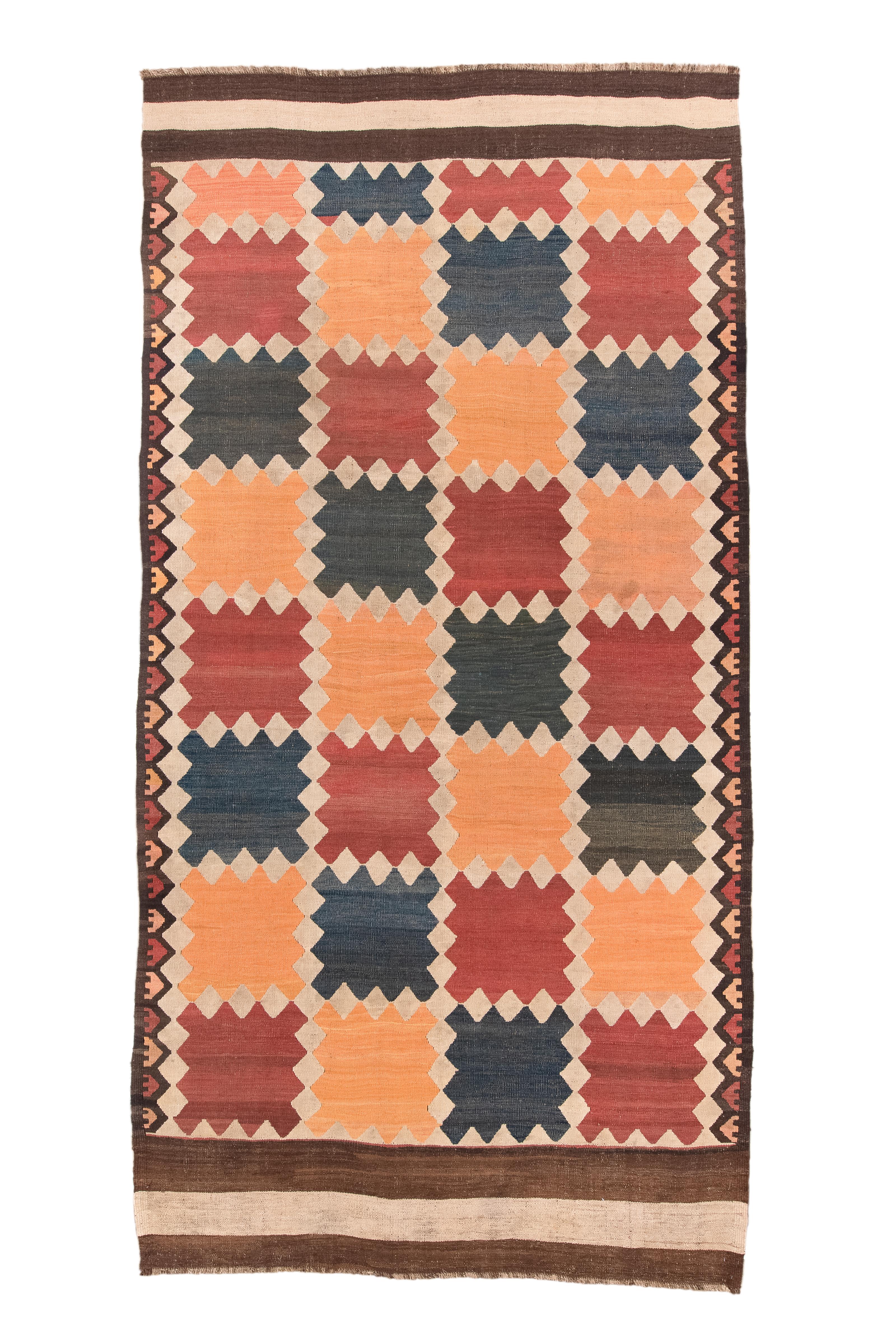 In seiner Schlichtheit liegt die wahre Kunst des Handwerks. Wir stellen den lebhaften Tazik-Kilim vor, der 1920 in sorgfältiger Handarbeit hergestellt wurde. In kontrastierenden Schattierungen von bernsteinfarbenem Glanz und dunklem Braun gewebt,