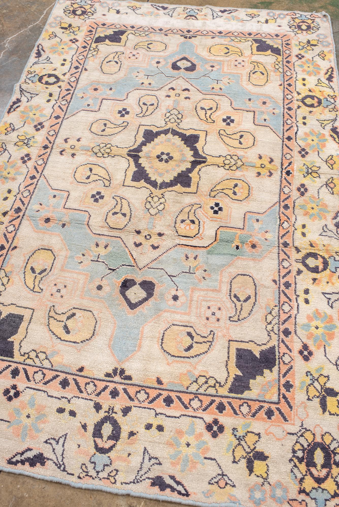 The pale blue field holds a broadly stepped ecru medallion decorated with botehs and central octogramme with floriated pendants. Similar ecru corners with botehs. Sand main border with petal palmettes, leaves and buds. From Eliko Rug Gallery 

Rug