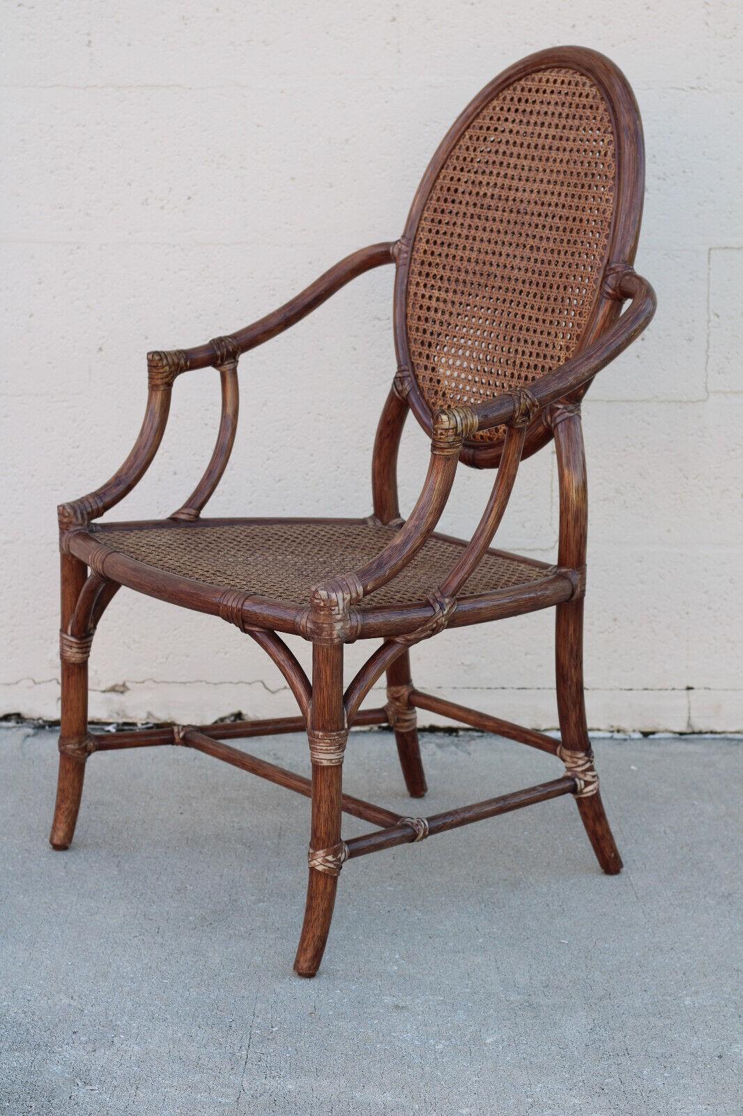 A set of four graceful and airy dining chairs designed by breakthrough innovator Elinor McGuire. Chairs have an oval rattan double-caned back and the original tobacco brown finish. This vintage set of arm chairs has McGuire’s trademark rawhide
