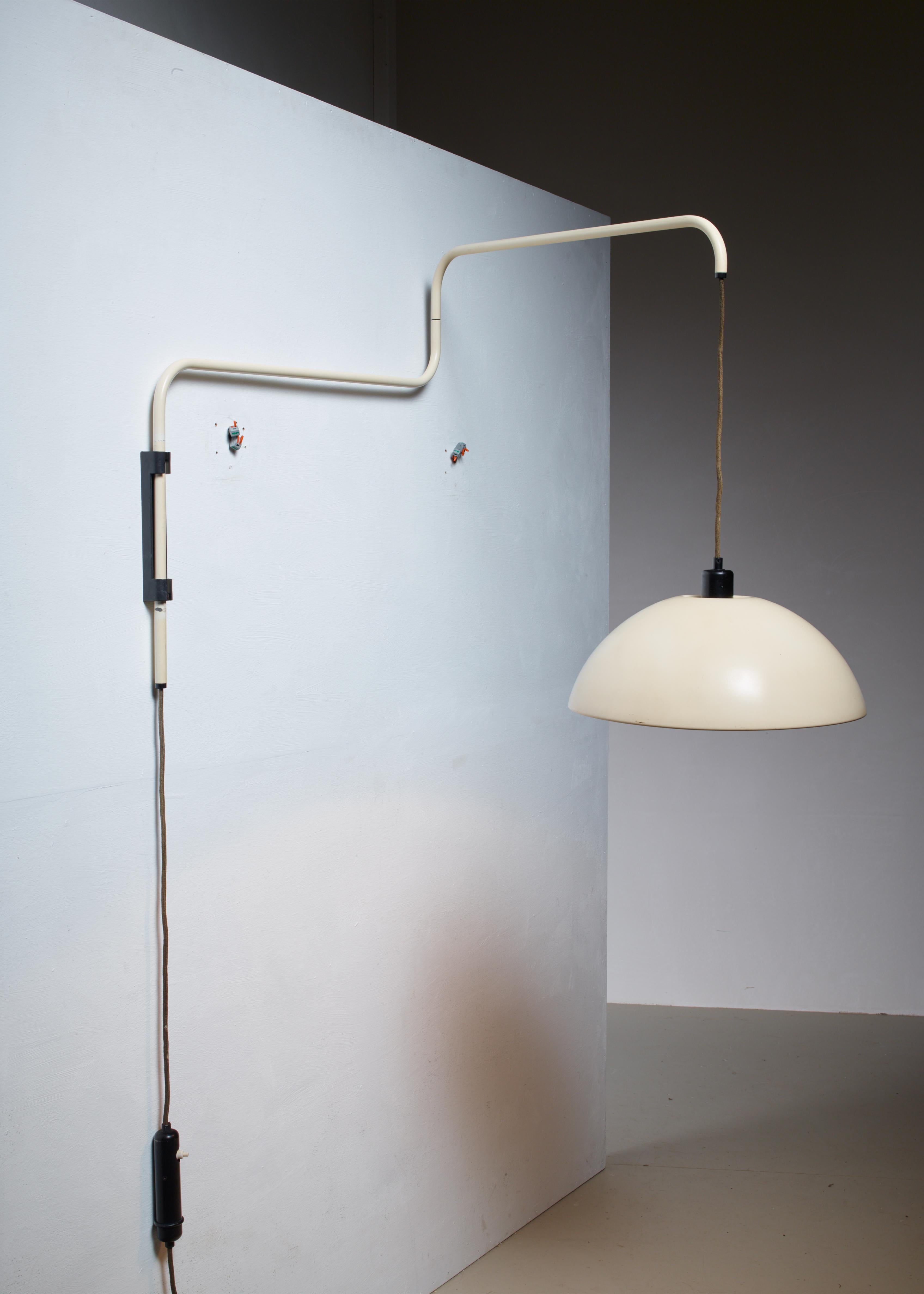 A Mid-Century wall lamp by Elio Martinelli for Martinelli Luce, made of off-white lacquered metal. The lamp has a swiveling, fully adjustable stem. The 40 cm diameter shade is height adjustable with a black steel counterweight with integrated light