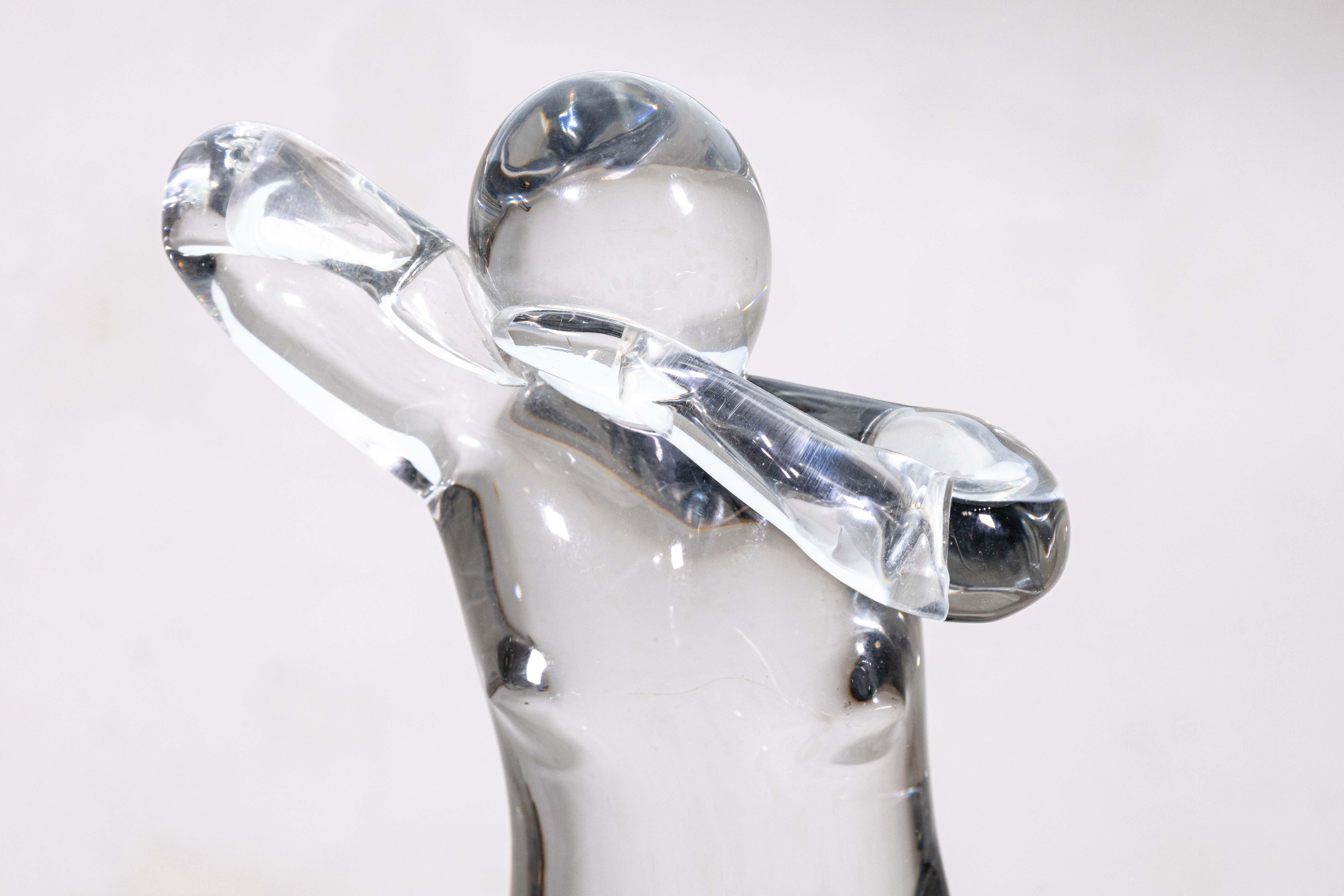 Una escultura de mesa figurativa de mujer de cristal de Murano de Elio Raffaeli para Salviati. Esta impresionante escultura de cristal muestra una figura femenina congelada en una pose dinámica, con los brazos levantados hacia la cabeza. La pieza se