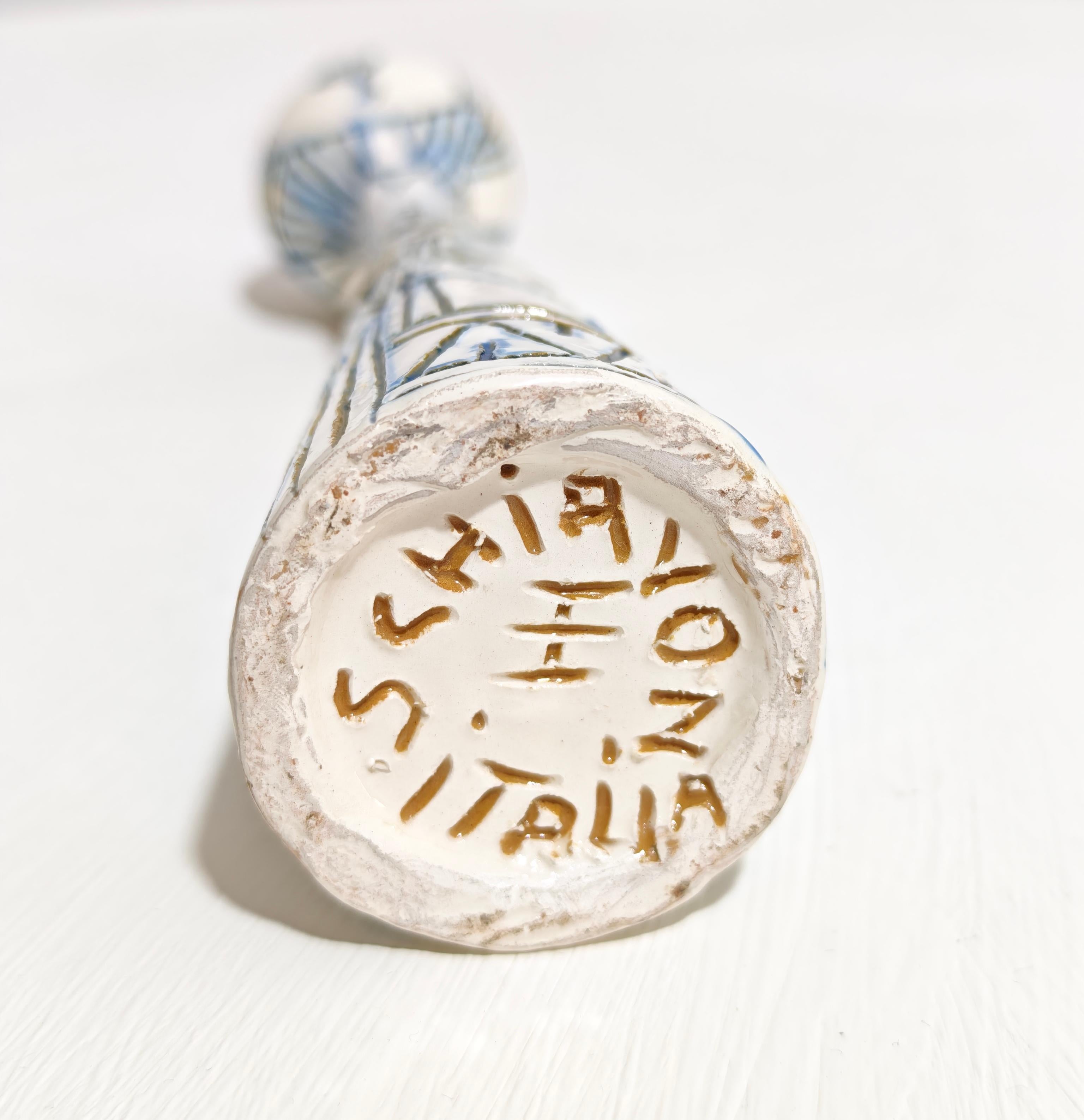 ELIO SCHIAVON. Fabricado en Italia hacia 1960.
Jarrón de cerámica con figura humana, esmaltado en blanco y decorado con grabados azules y negros. Firma en la base. Un objeto decorativo que no debes subestimar.  Por favor, mira atentamente el vídeo y