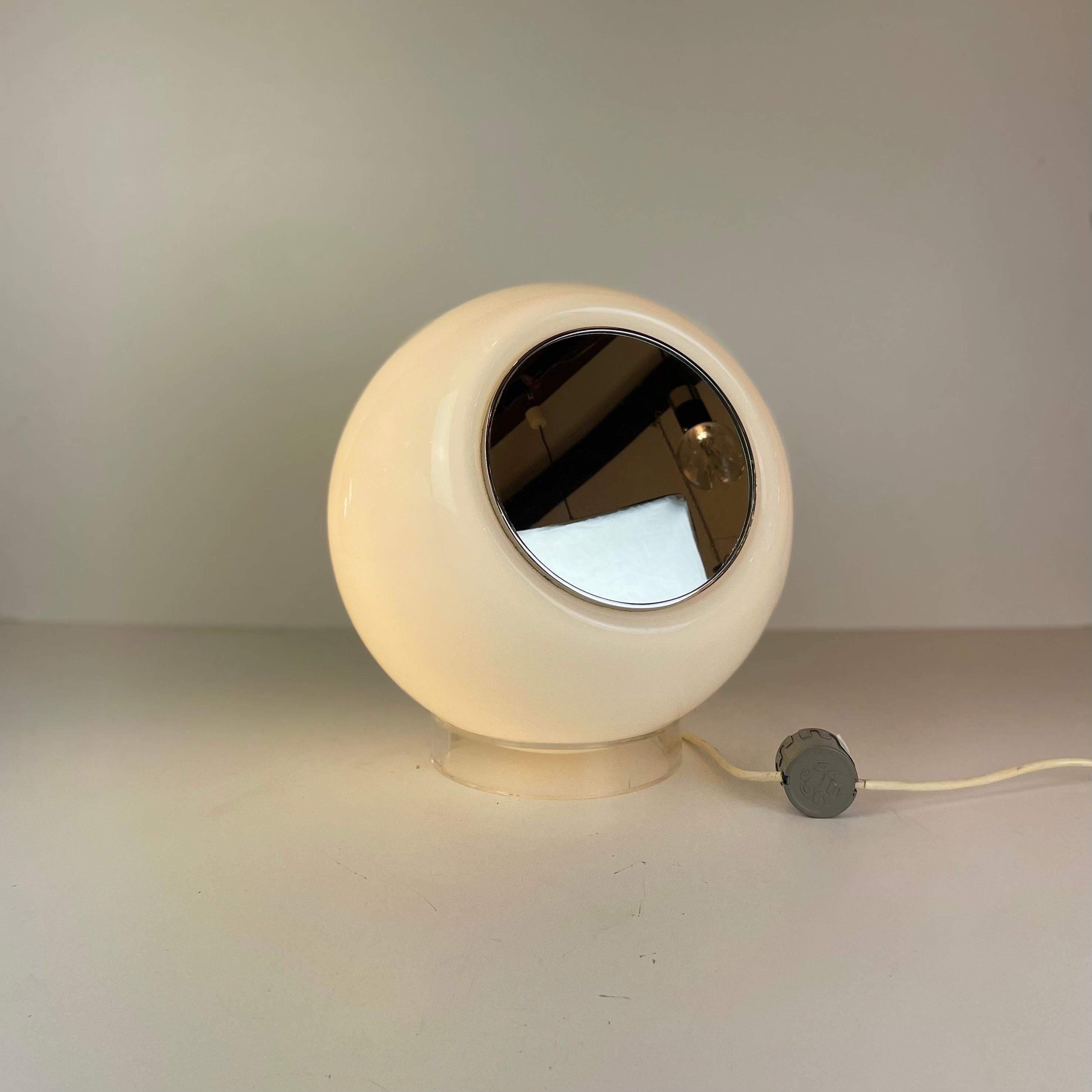 Rara lampada da tavolo dell'era spaziale, chiamata Elios e realizzata in vetro soffiato bianco di Murano, disco cromato e base in acrilico che permette di regolare la direzione dello specchio. Disegnata nel 1977 da Giusto Toso per l'editore italiano