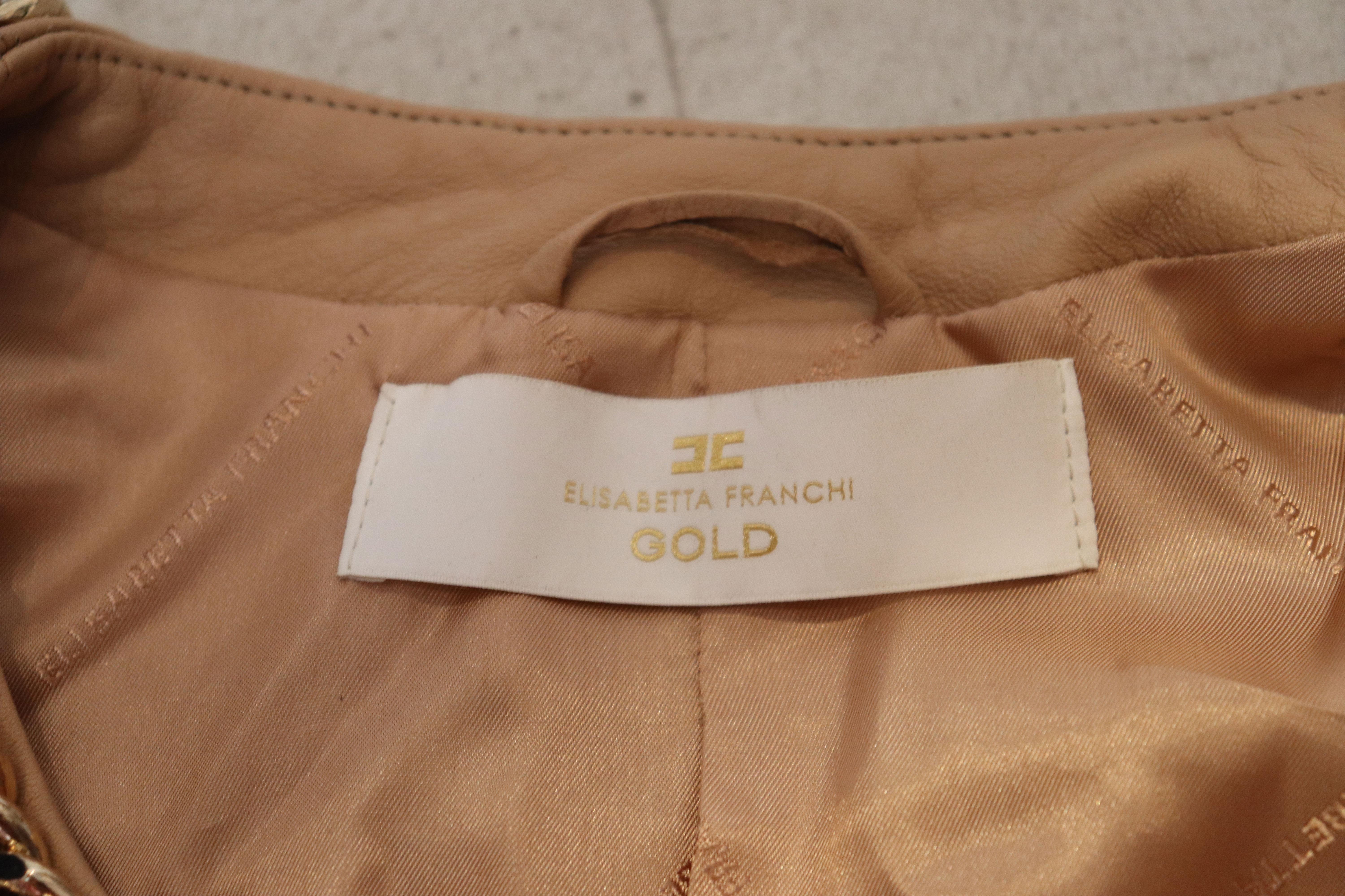 A super soft leather bolero/short jacket by Elisabetta Franchi. In a biscuit colour leather with chain detail around the neck and front. The jacket fastens with hoooks and eyes,has ruffle edged sleaves and is fully lined.