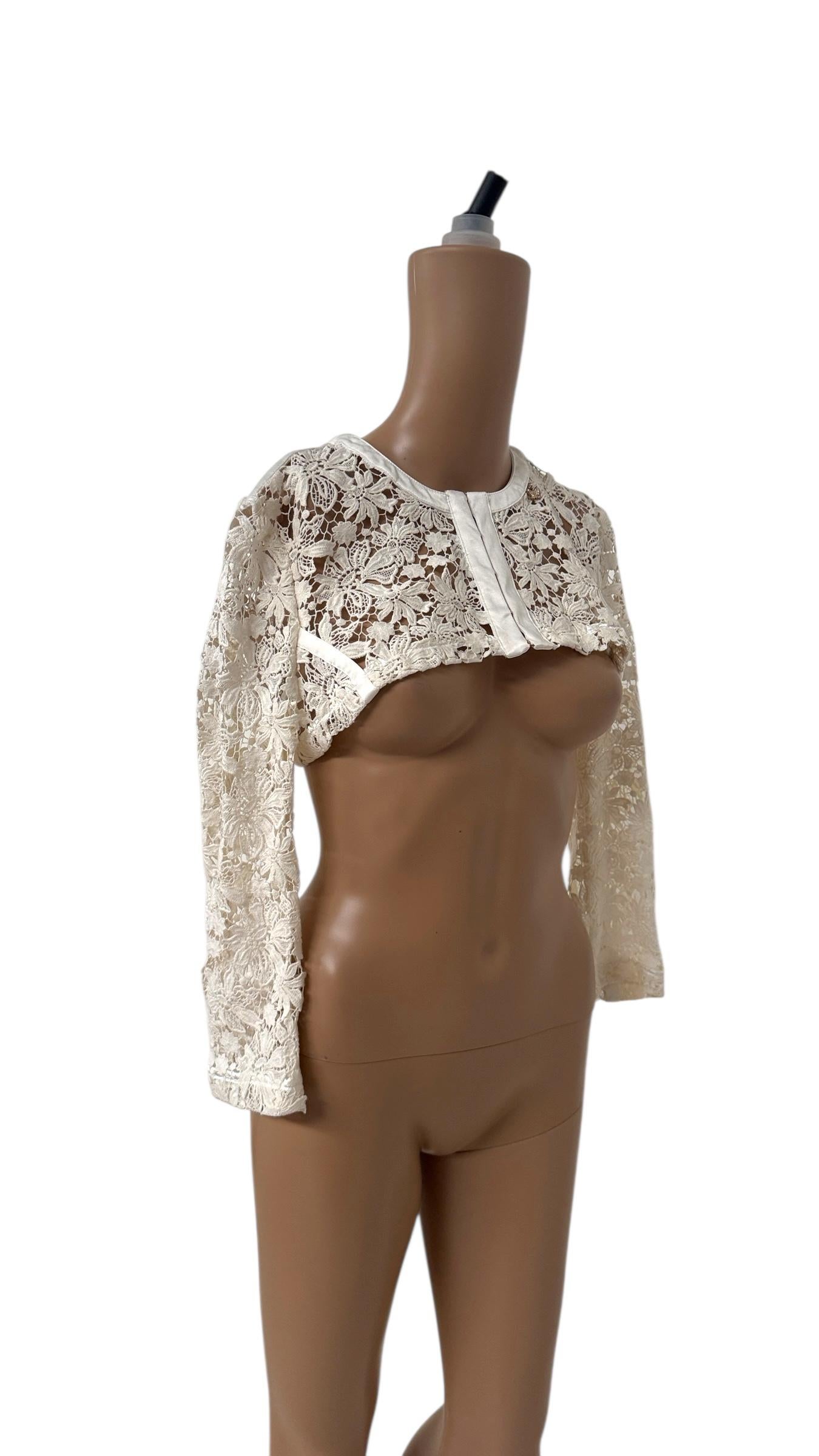 An elegant and romantic bolero shrug from the Spring/Summer 2012 collection by Italian designer Elisabetta Franchi. This refined piece is crafted from intricate ivory floral lace and finished with ivory satin trim along the edges, neckline, and