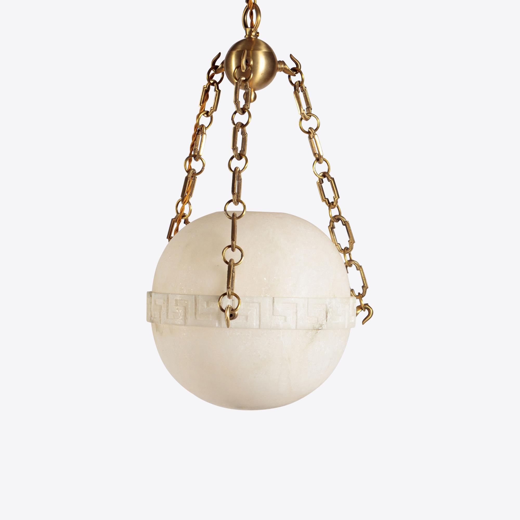 A beautiful carved alabaster globe is suspended from brass chains to create a hanging lantern. The alabaster features a classical Greek key motif while the brass chain and ball add to the traditional beauty of this lantern.