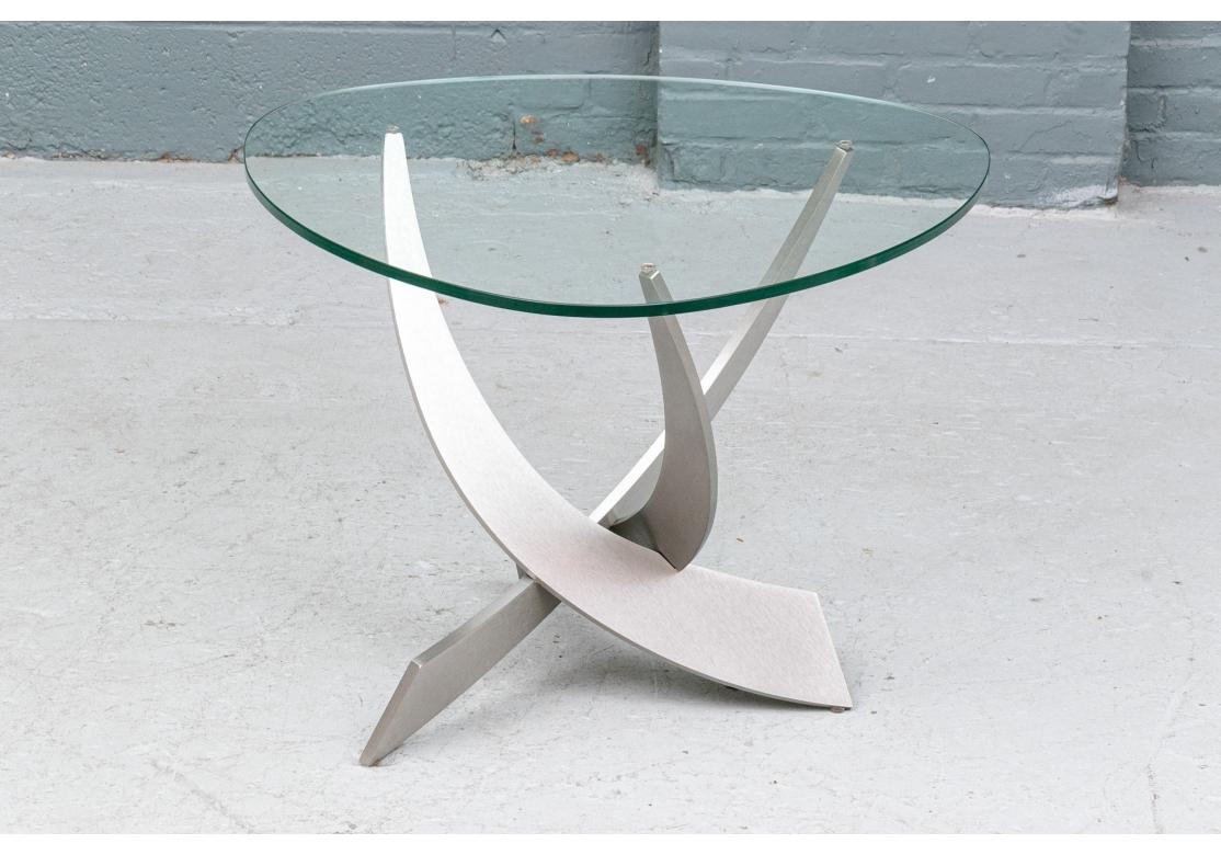 Dieses elegante Design aus dickem, massivem Stahl mit einer glänzenden, champagnerfarbenen Oberfläche erinnert eher an eine Skulptur als an ein Möbelstück. Der Tisch verfügt über drei ineinander greifende Arme, die die Glasplatte stützen. Die weiche