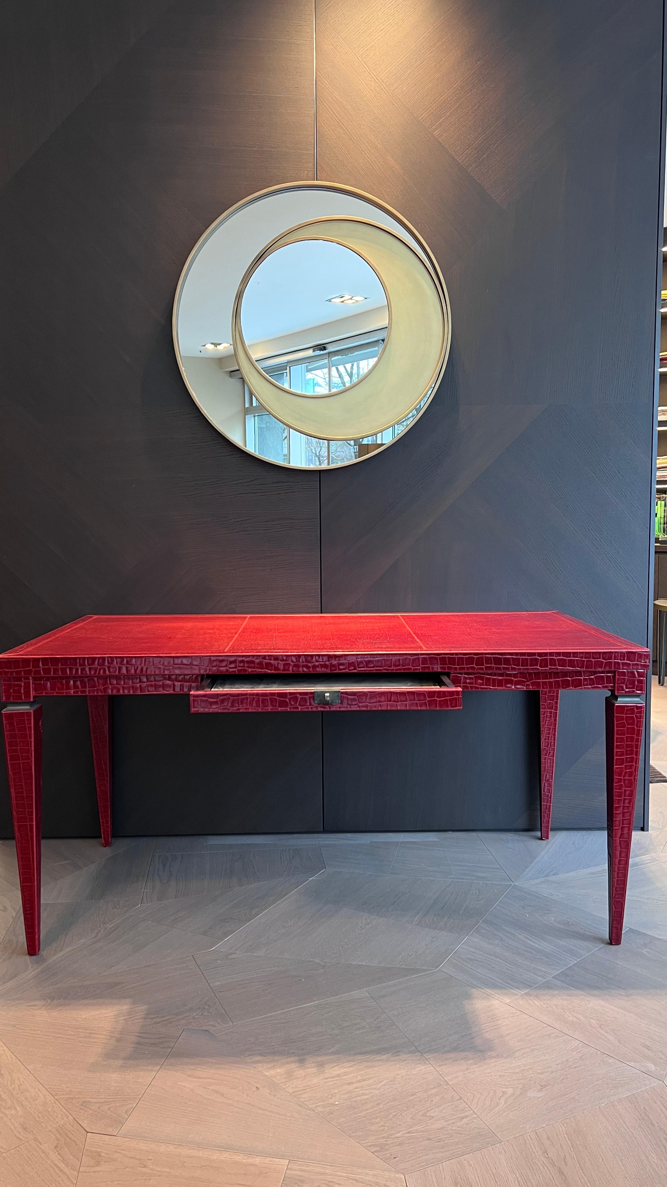 Der Elitis-Schreibtisch ist ein Ausdruck von Luxus und Raffinesse. Dieses elegante Möbelstück mit einer einzigen Schublade ist in rotes Leder mit Krokodilprägung gehüllt, das einen Hauch von Raffinesse verleiht. Die dunklen Bronzedetails