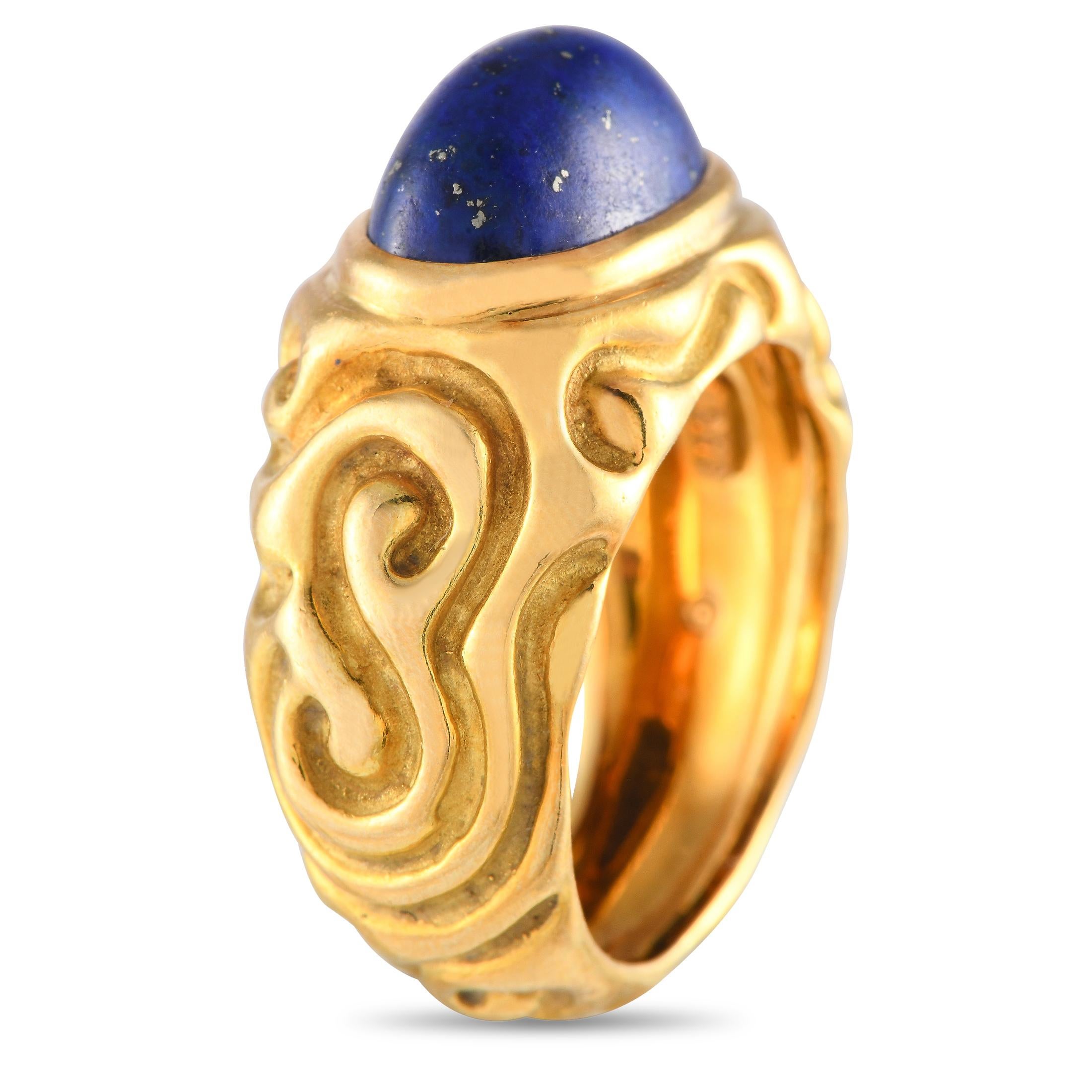 Here is a bold and striking cocktail ring from British master goldsmith and jewelry designer Elizabeth Gage. This handcrafted ornament of luxury features a solid yellow gold band with carved soft swirls and curved lines. An oval lapis lazuli