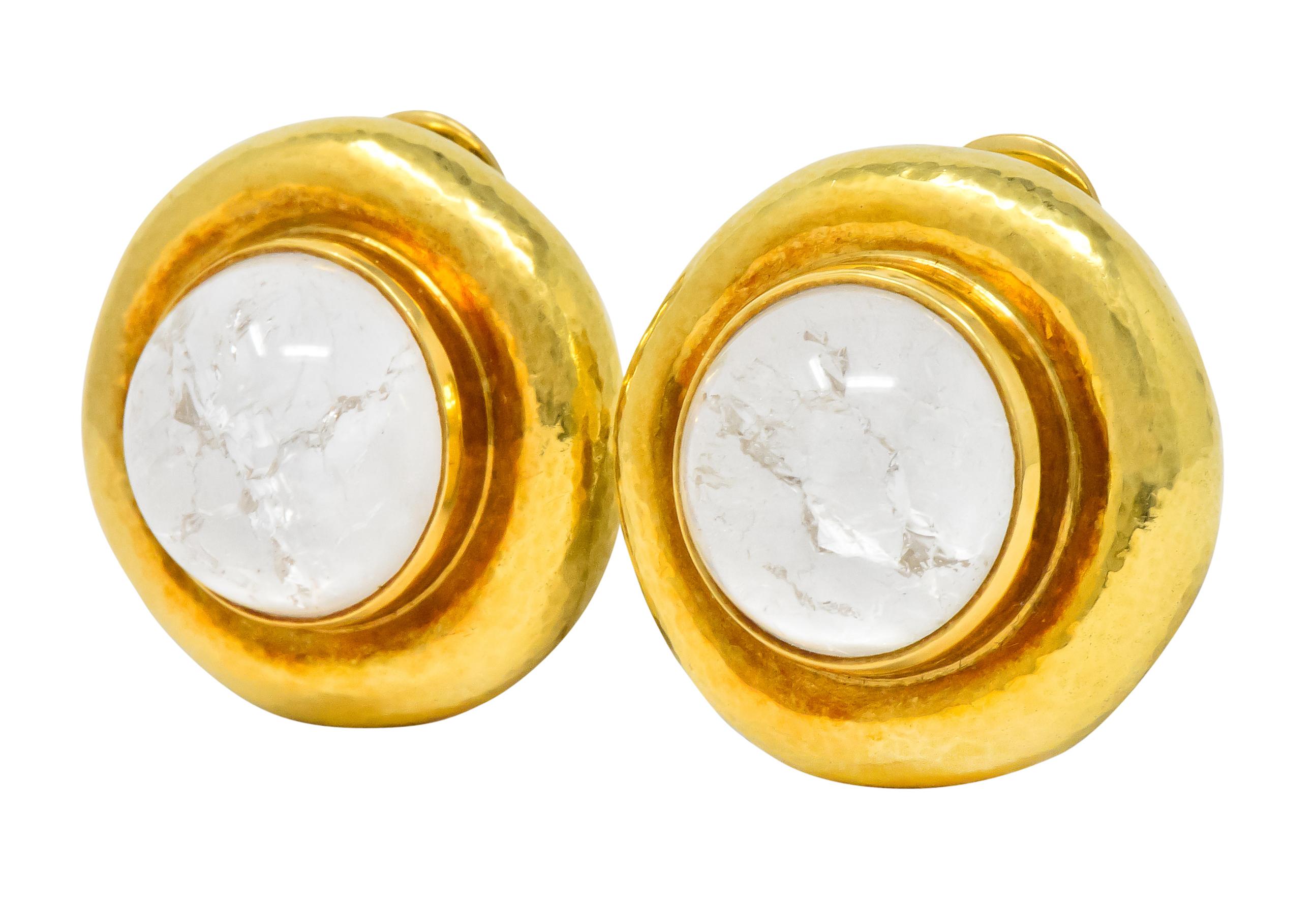 Each centering a high round cabochon rock crystal, with natural crackle or fissures, measuring approximately 17.0 mm

Backed by white mother of pearl

Bezel set in high polished gold with a rounded hammered gold surround 

Hinged clip backs

Signed