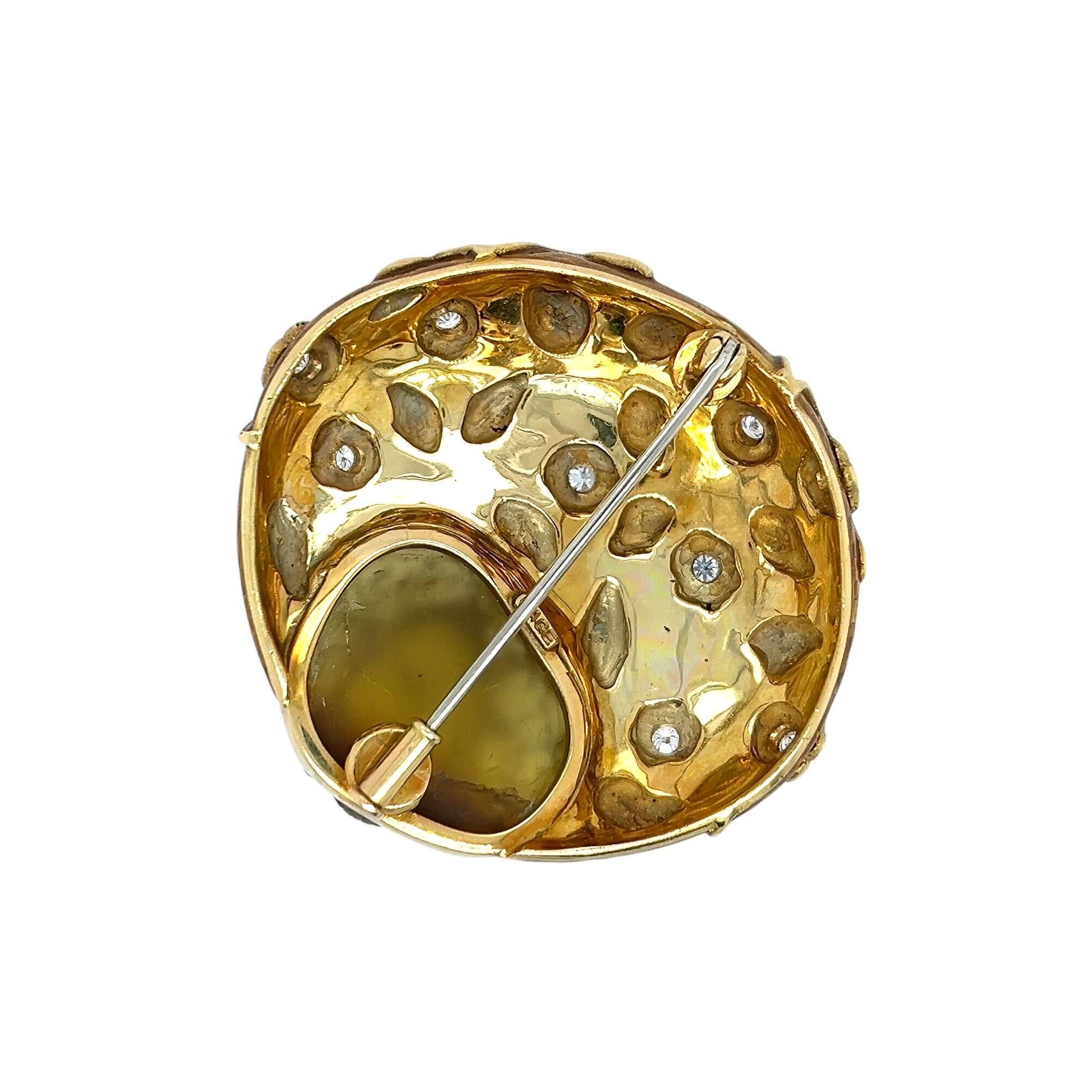 An 18 karat yellow gold, brownish green stone, enamel and diamond brooch, Elizabeth Gage.  Designed as a bezel set brownish green stone carved in the form of a honeybee with black enamel eyes embraced by a crescent decorated with golden enamel and