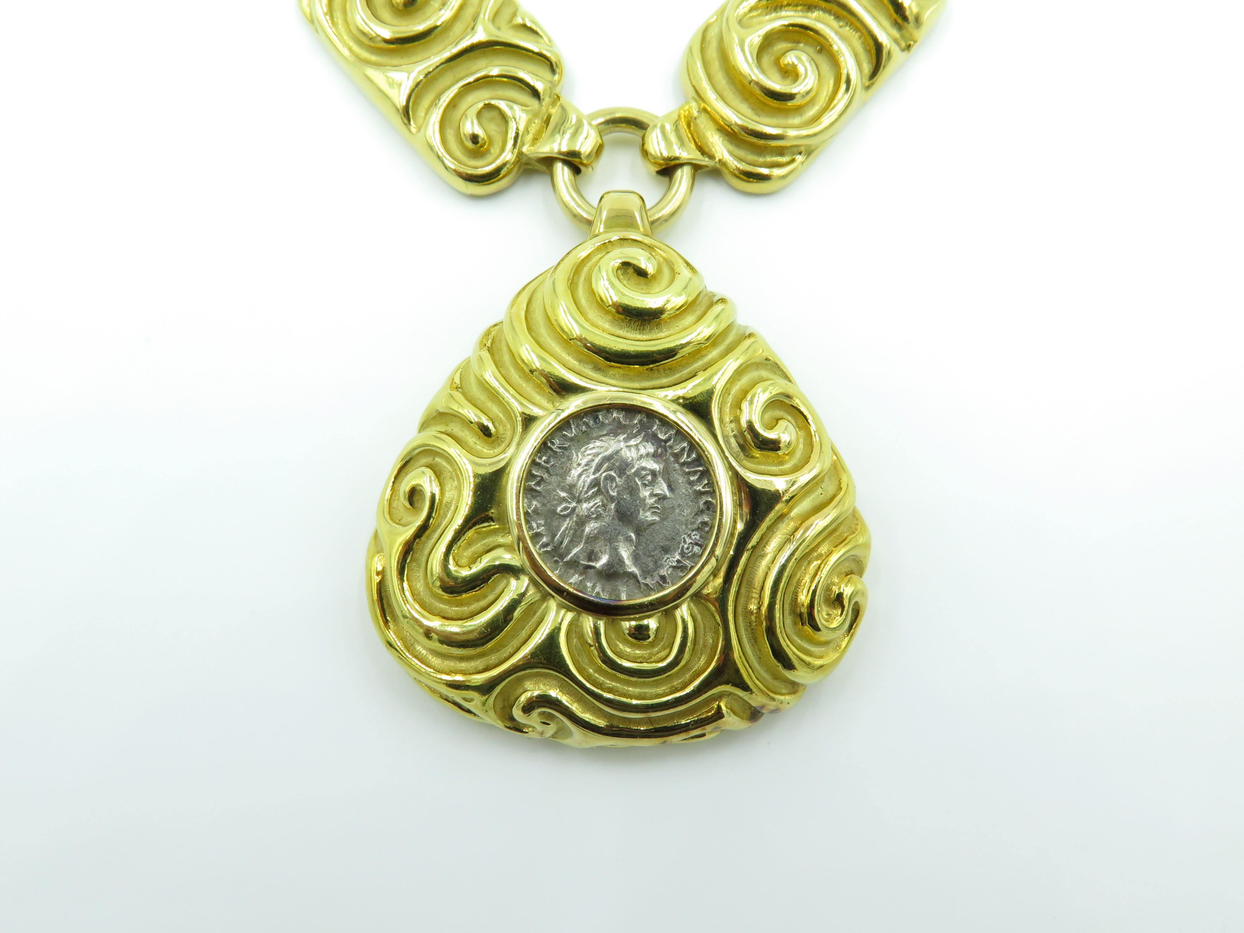 An 18 karat yellow gold and ancient coin necklace. Elizabeth Gage. Circa 1990.  Of Etruscan inspired design, suspending a textured gold shield shaped pendant, decorated with a scrolling design, centering an ancient coin depicting a man in profile,