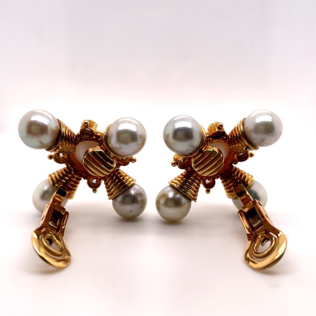 A pair of Elizabeth Gage pearl and diamond 18 karat yellow gold clip earrings, circa 1990.

This iconic pair of earrings are each designed as a fluted cruciform with a mabe pearl to its centre and further pearls to each ridged polished yellow gold