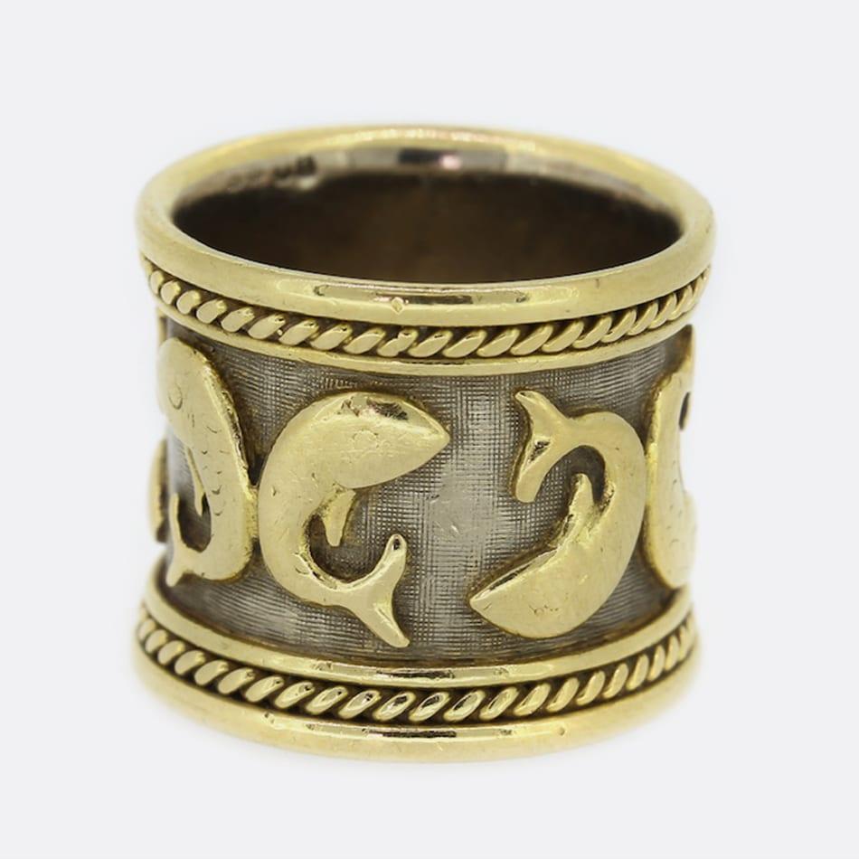 This is an 18ct yellow gold band ring from the luxury jewellery designer Elizabeth Gage. The ring forms part of the Zodiac collection and is the Pisces model. The ring is decorated with four Pisces motifs with white gold bead detail and is finished