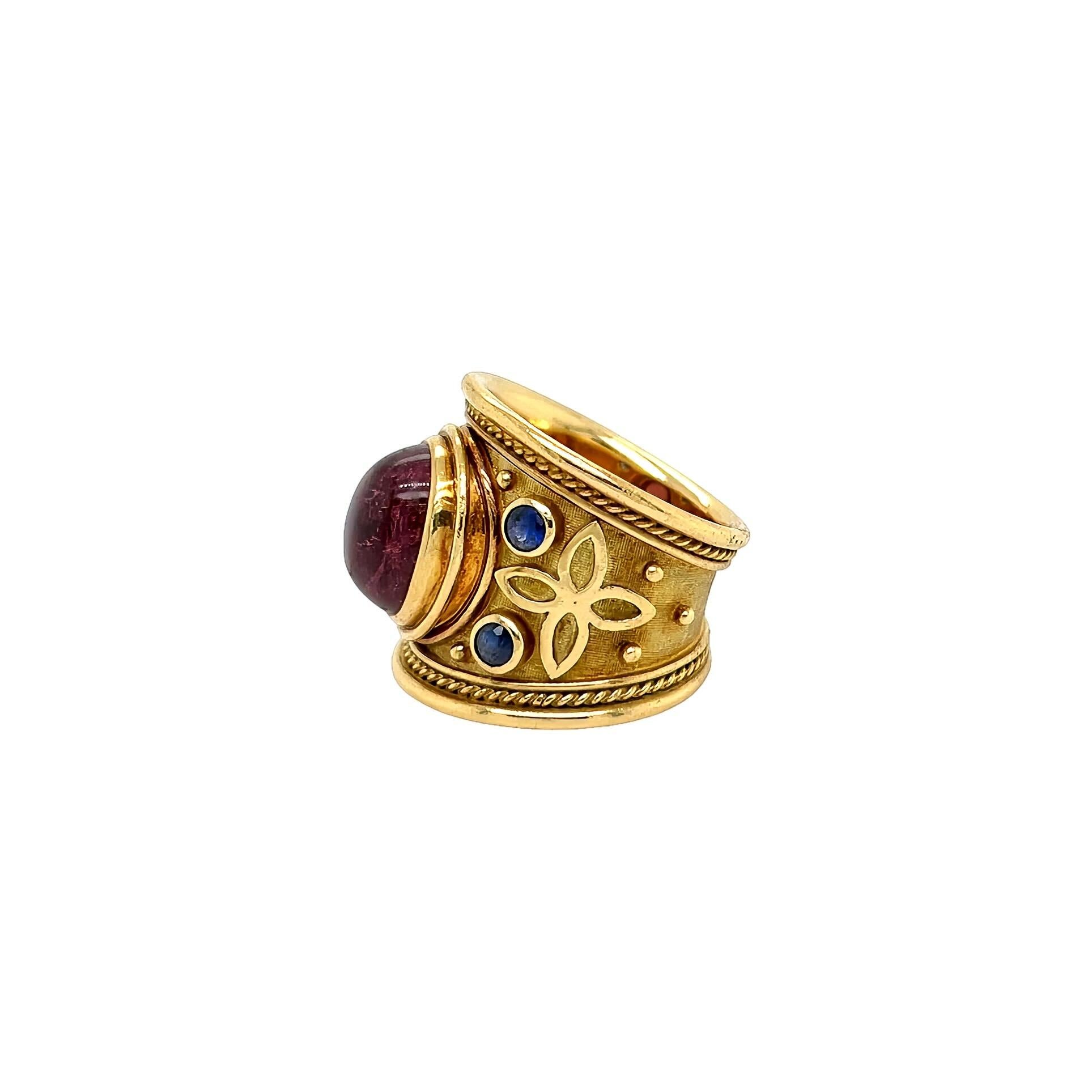 Anello in oro giallo 18 carati, tormalina rosa e zaffiro, Elizabeth Gage.  L'anello templare è disegnato come una fascia con bordi modanati che racchiudono un motivo a corda che centra una tormalina rosa ovale cabochon incastonata, affiancata da