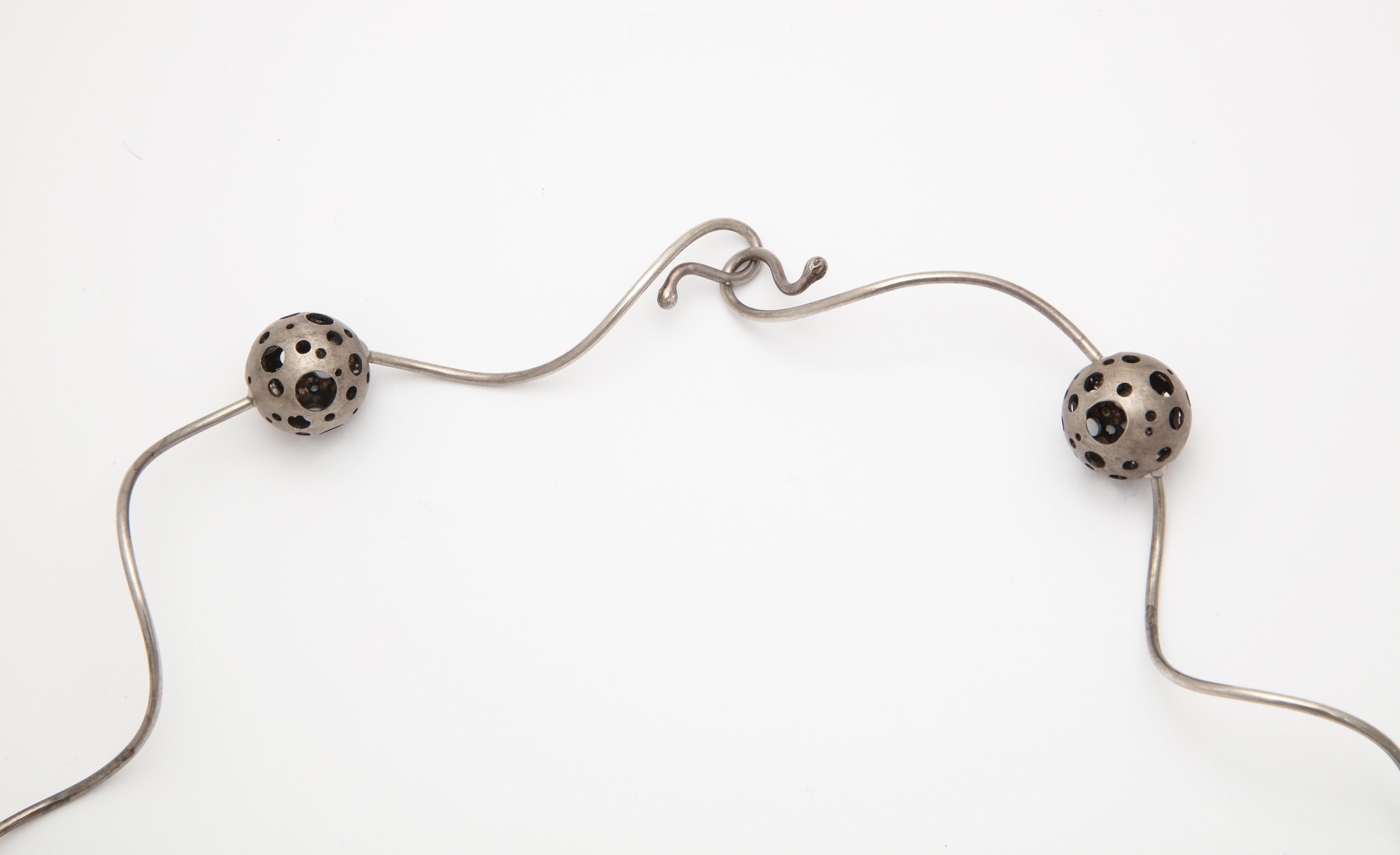 A wonderful modernist silver necklace with 9 pierced spheres threaded through with curly silver rods