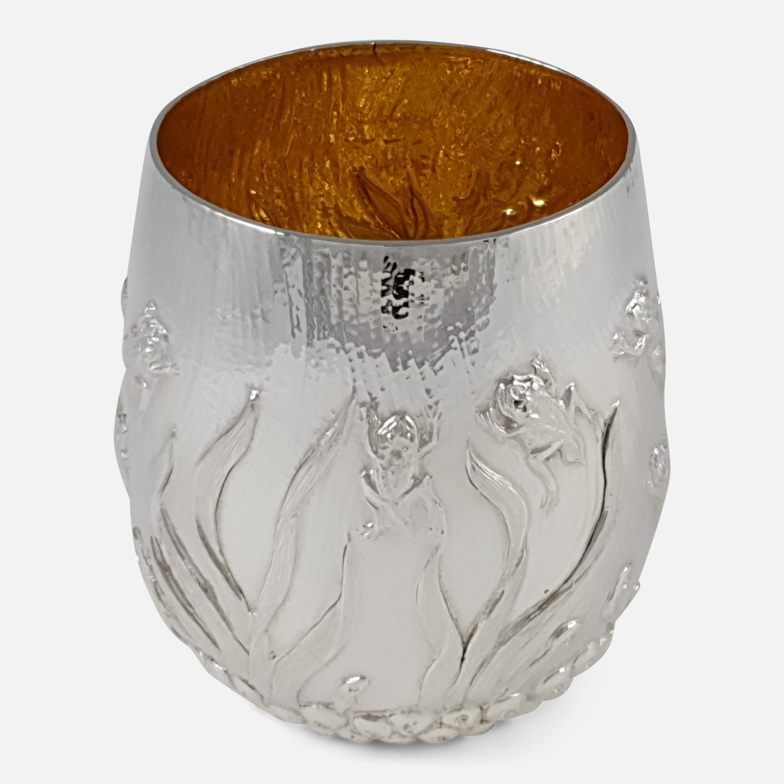 An Elizabeth II sterling silver gilt beaker made by Garrard & Co. Limited. The beaker, with gilt wash interior, is of tapering cylindrical design, depicting a chased scene of frog spawn to the base, leading to tadpoles and frogs emerging swimming
