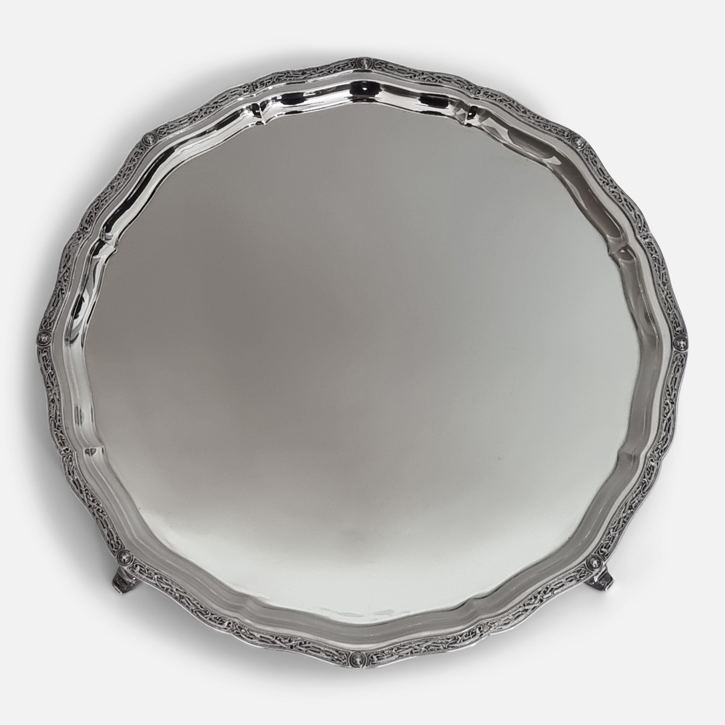 An Elizabeth II Sterling Silver Salver. The salver is of plain ground, with an applied Lindisfarne decoration to the shaped and incurved border, and sitting on four mystical creature feet.

The original associated booklet detailing some of the