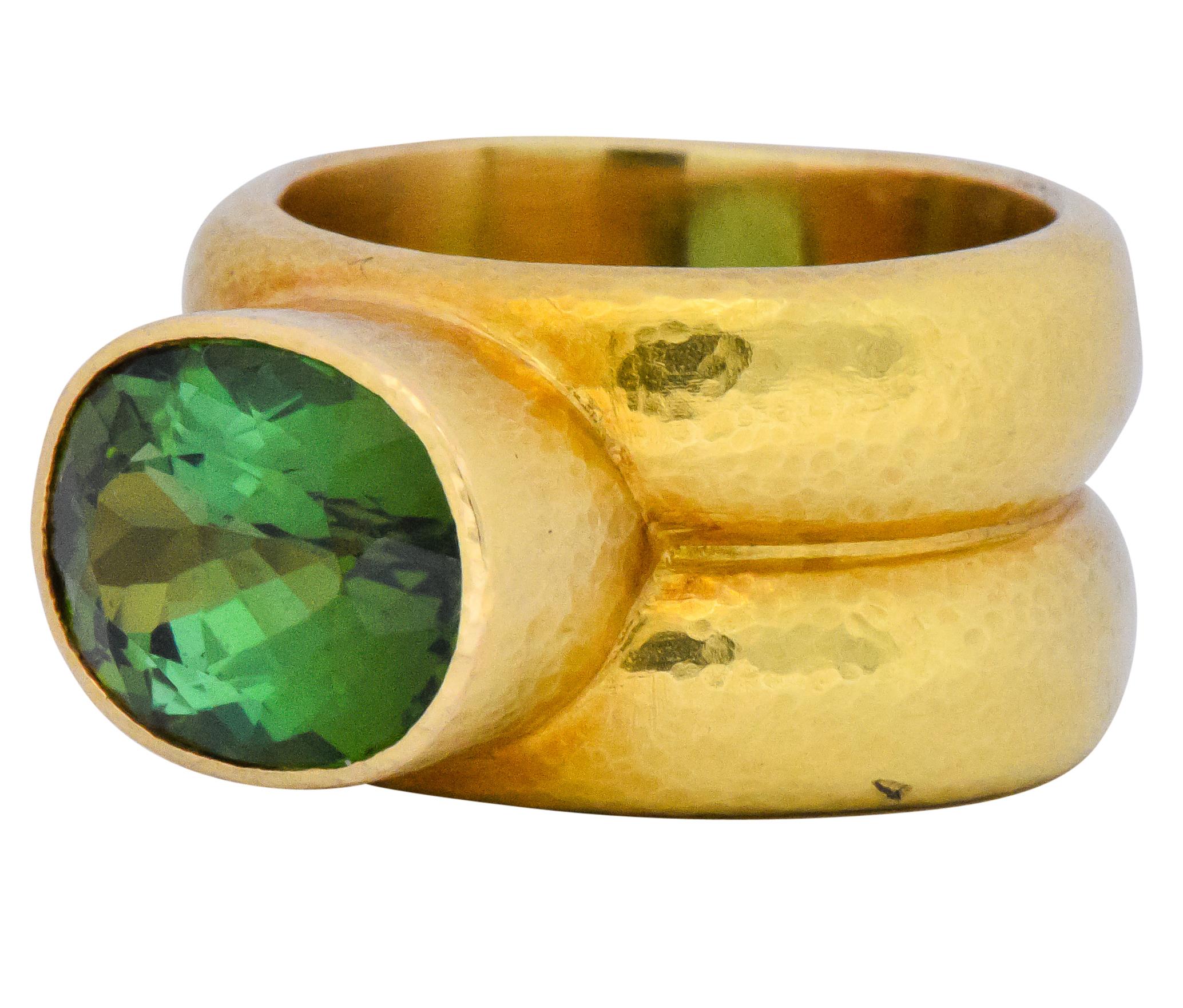 Centering an oval cut tourmaline weighing approximately 4.00 carats

Displaying lively blue and yellow green hues

Bezel set in hammered gold double shank

Tested as 18 Karat

Ring Size: 5 1/2 & not sizable

Top Measures: 9 mm and sits 7 mm