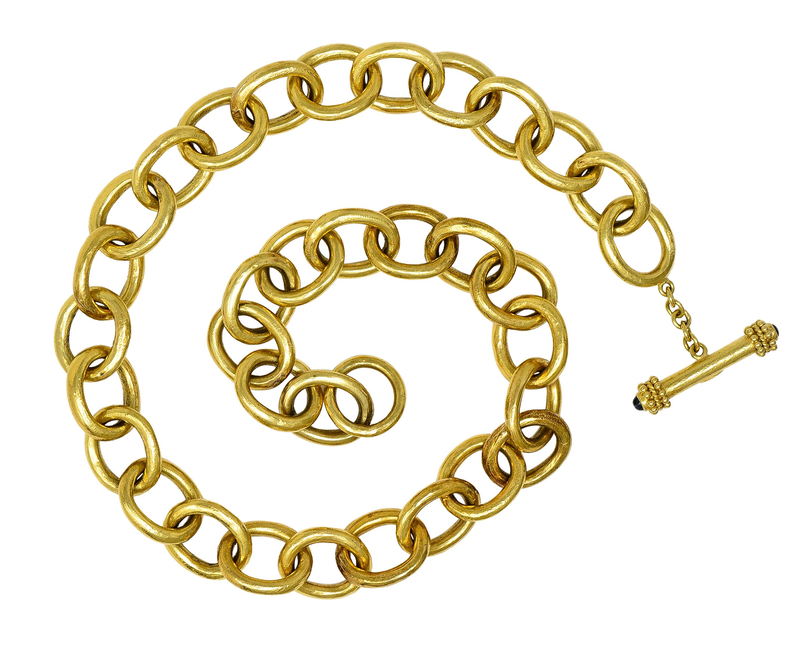 Designed as a cable link chain comprised of large oval-shaped links 
With very fine organic texture throughout 
Completed by a stylized toggle clasp closure 
With gold bead and twisted rope terminals 
Capped with 3.0 mm round sapphire