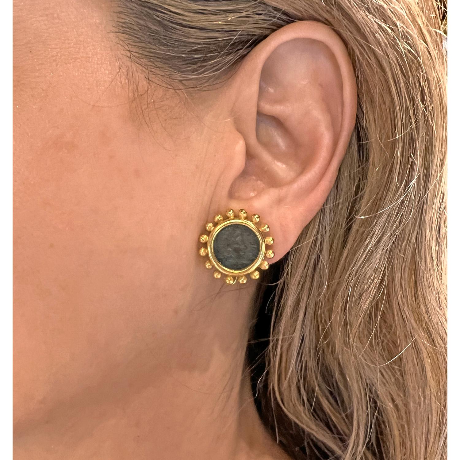 Crafted in 19 karat yellow gold, these Elizabeth Locke earrings center bezel-set ancient bronze coins. The circular design is framed by Locke's signature beaded gold border. Stamped '19k' with Elizabeth Locke design mark. French omega style clip