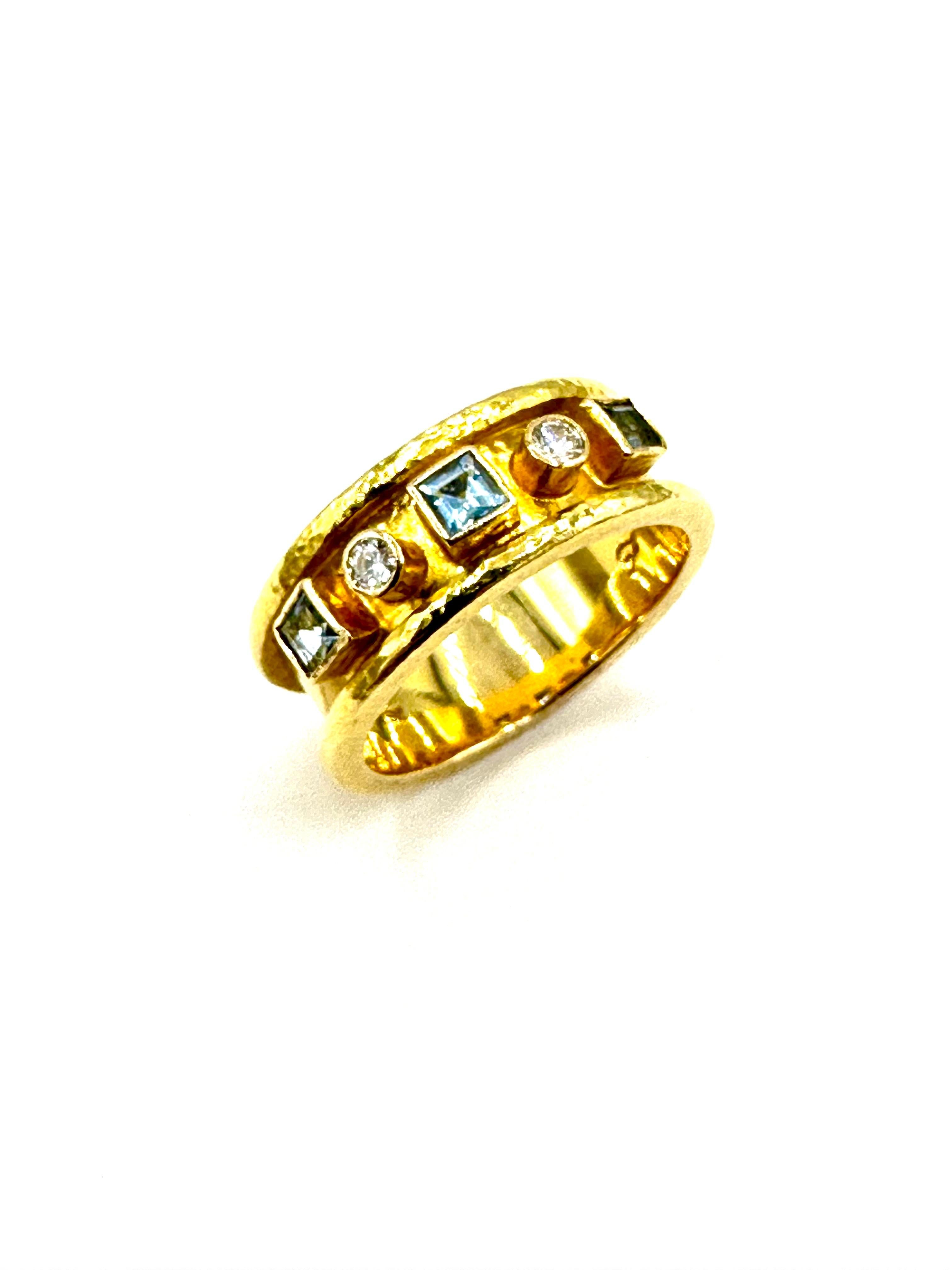 This is an easy to wear design by Elizabeth Locke.  The ring contains three square cut Aquamarines with two round brilliant Diamonds, bezel set in the center channel of the ring.  The ring is made in 19K textured yellow gold, and is currently a