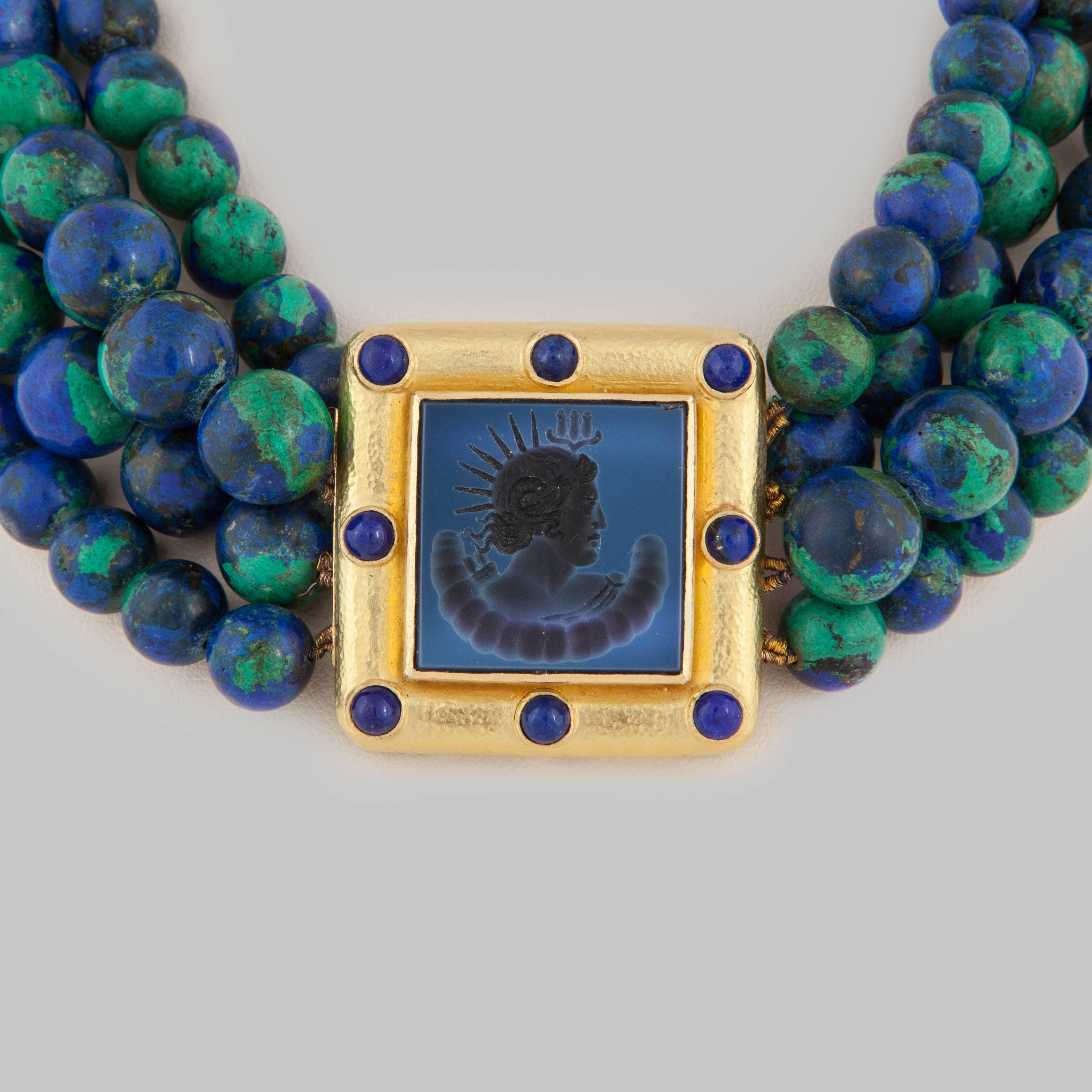 Elizabeth Locke multi-strand necklace consisting of 260 azurmalachite beads.  The necklace features a central plaque in 18K gold with eight cabochon lapis stones and a carved intaglio center.  Inside bead strand measures 14 inches; the plaque
