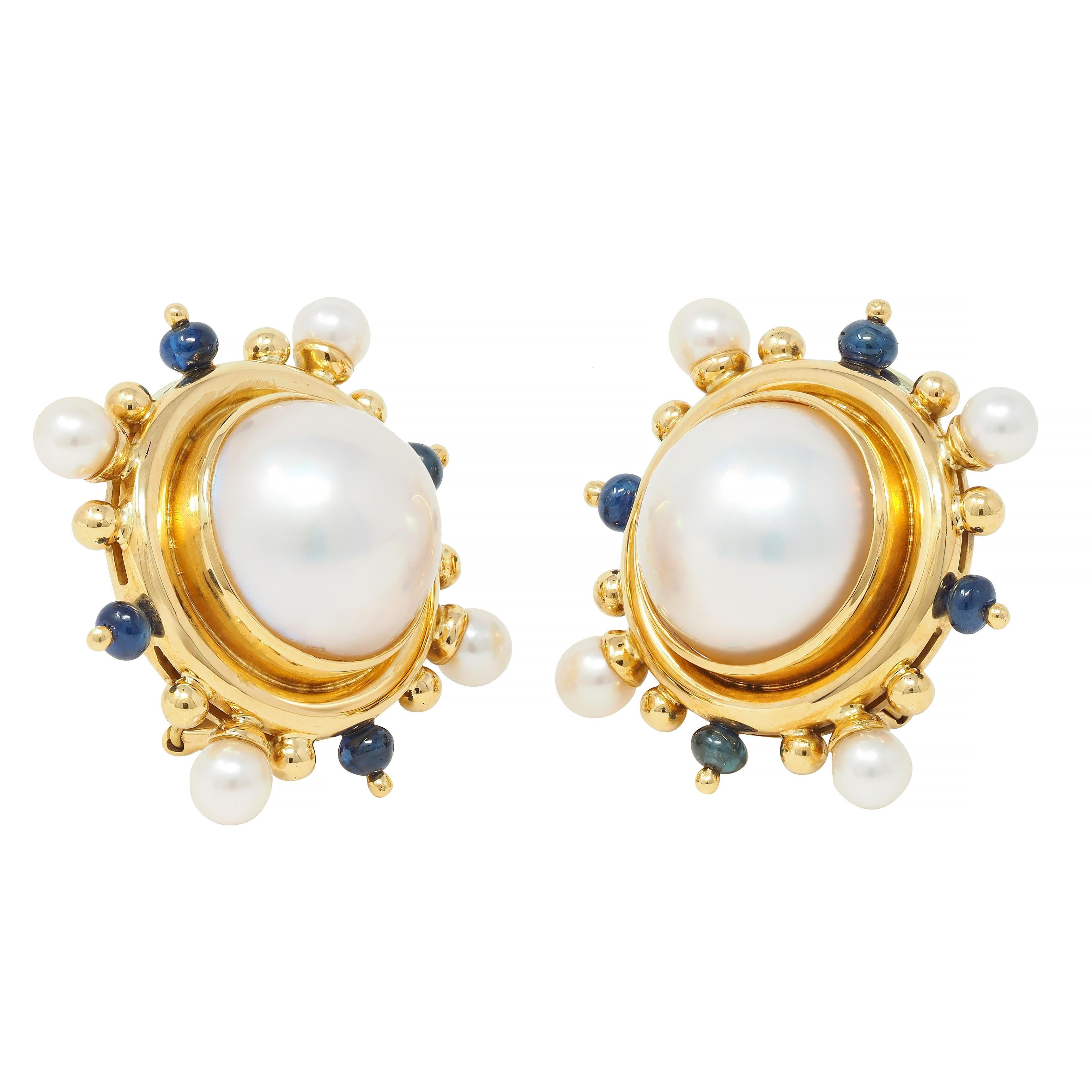 Centering a 14.0 mm round button pearls - white in body color with strong iridescence
Bezel set with well-matched 4.5 mm round pearls in ridged surround 
Featuring a radial burst pattern with gold and sapphire beads 
Sapphire beads measure 3.0 mm