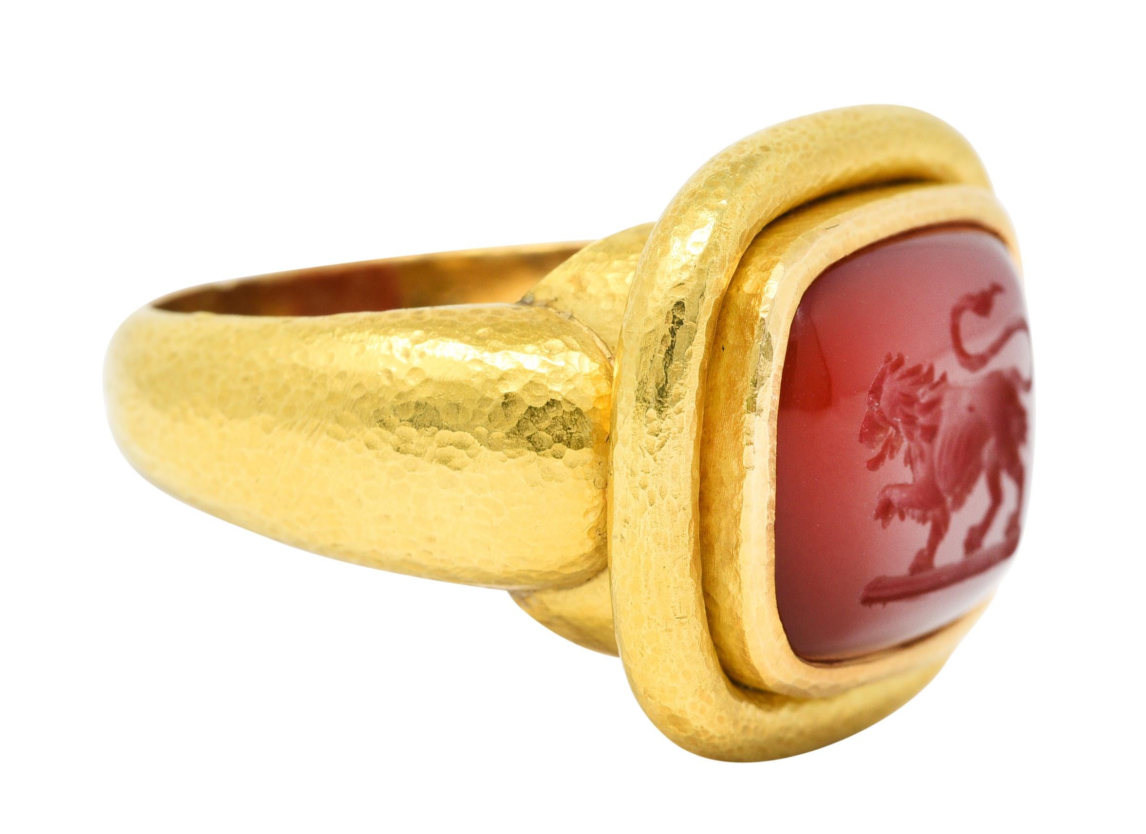 Mit einem Cabochon aus Karneol im Kissenschliff von ca. 14,0 x 11,2 mm

Transluzent mit einheitlicher ziegelroter Farbe und tief geschnitzt mit einem Löwen

Die Lünette ist in eine tief geriffelte Einfassung eingefasst und wird durch eine gehämmerte