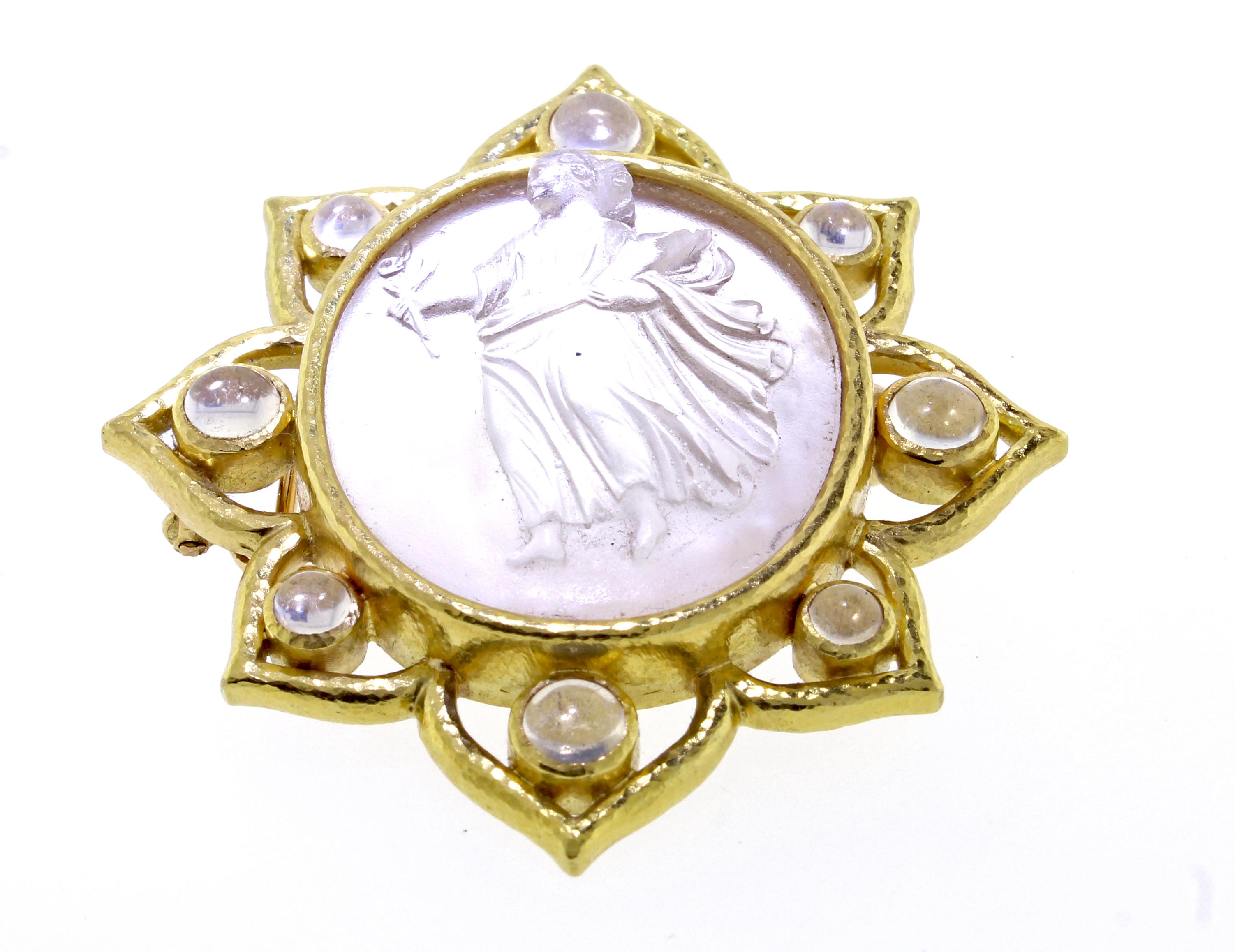 From acclaimed jeweler, Elizabeth Locke, this 19 Karat gold brooch. The brooch- pendant combination boasts a carved clear glass over mother of pearl cameo. The oval brooch  measures 2 by 2 ¼ inches. The cameo is set in an open gold border with