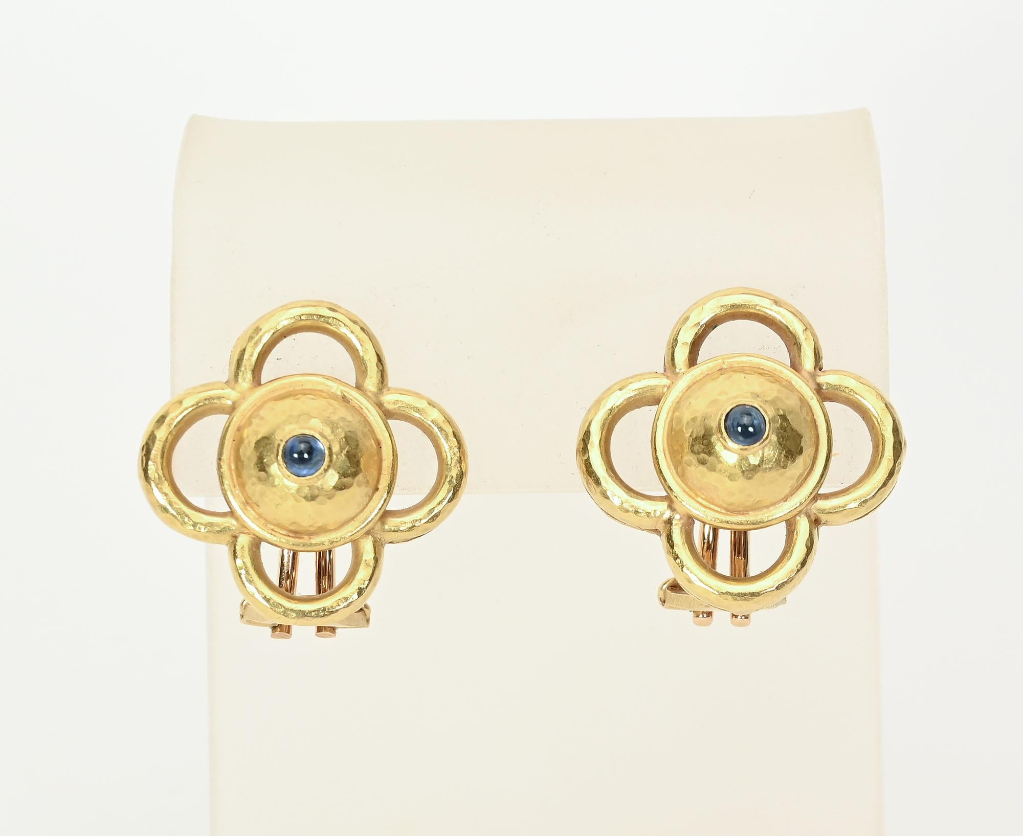 Unusual  pair of gold earrings by Elizabeth Locke. The center is a small cabochon sapphire set in a hammered gold dome. The dome  is surrounded by four open half circles. The earrings are 15/16