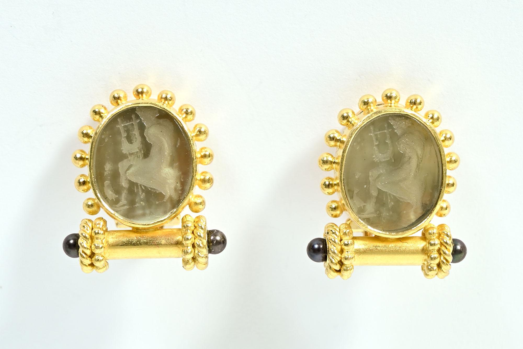 Die Ohrringe von Elizabeth Locke zeigen eines ihrer klassischen Lieblingsthemen: eine Frau, die eine Leier spielt. Die profilierte Stichtiefdruckfigur ist in grünes Glas geätzt und mit Goldkugeln umgeben. Darunter befindet sich ein runder