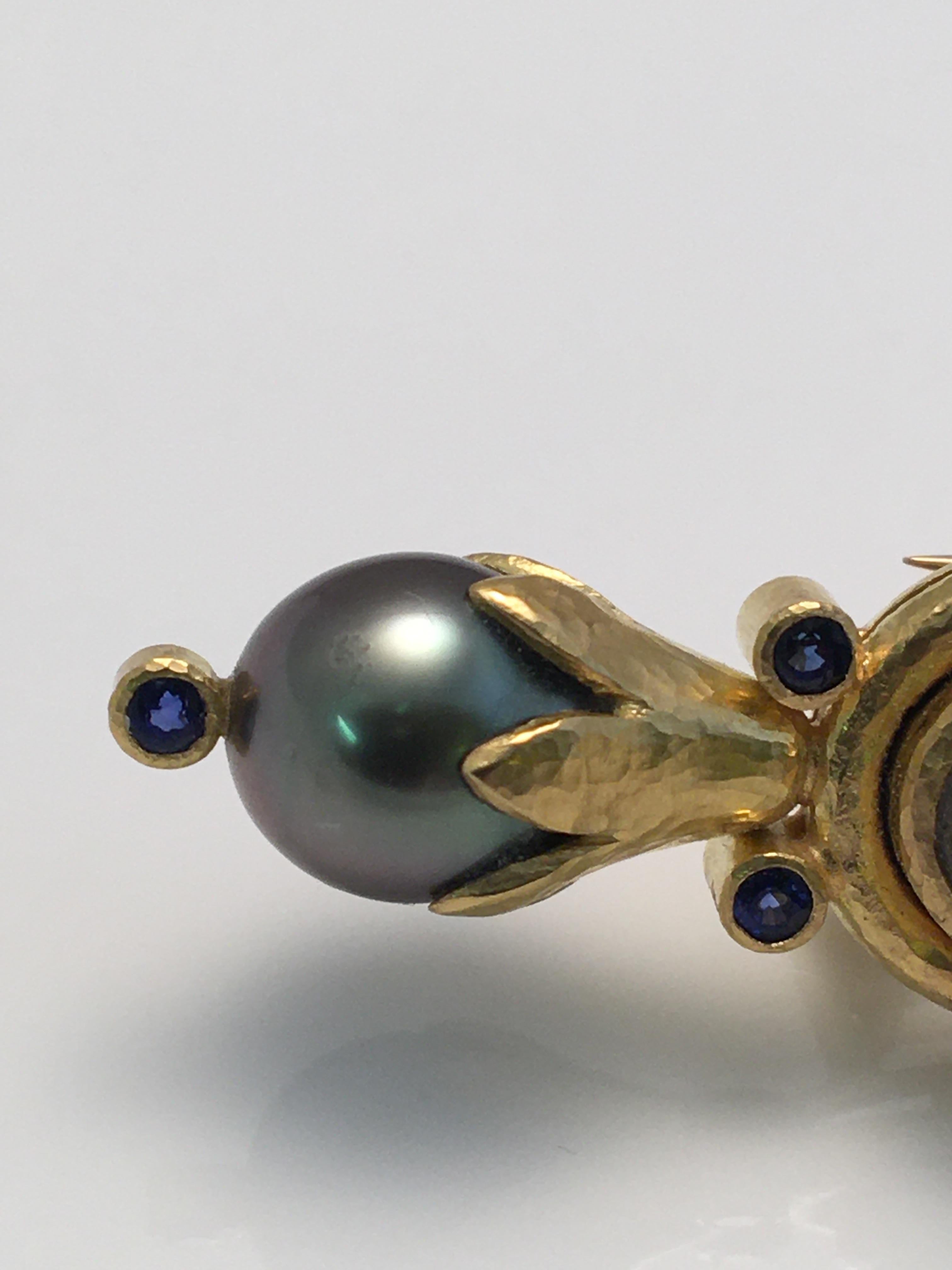 Elizabeth Locke
19 karat yellow gold
Oval labradorite approximately 18mm x 10mm
Two south sea black pearls, approximately 9.5-10.0mm
Six round blue sapphires, approximately 2.5mm each
Double pin hinged clasp with safety
Can be worn horizontal or