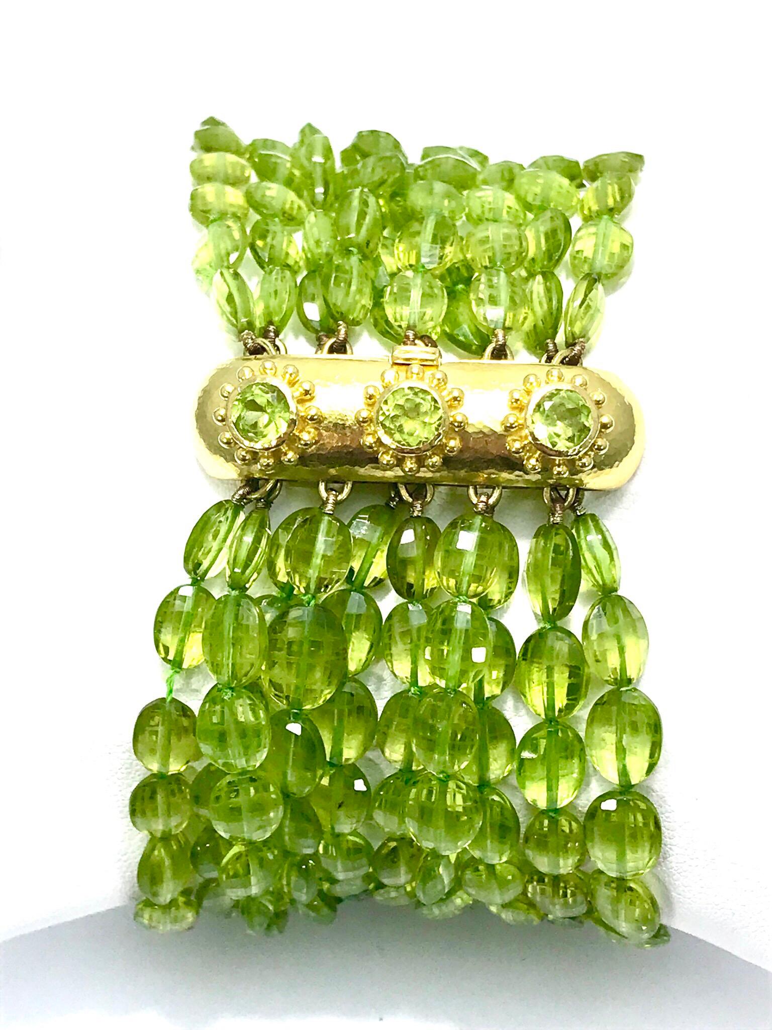 A beautiful ten strand vibrant lime green Peridot bracelet with a 18k yellow gold clasp designed by Elizabeth Locke.  The tourmaline strands are elongated beads and the clasp is set with three round faceted Peridot.  The clasp has the Elizabeth