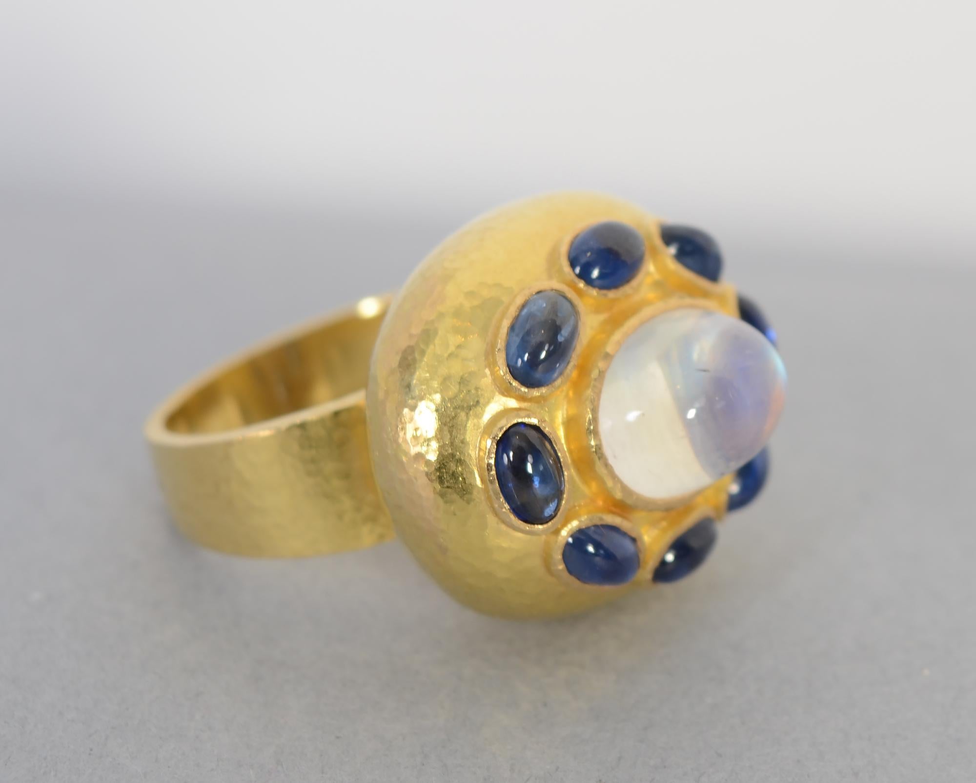 Elegant, restrained moonstone and sapphire ring by Elizabeth Locke. The center stone is a 4.15 carat oval, domed moonstone. It is surrounded by 8 oval sapphires . They are all set on a hammered gold oval cushion. The ring is 19 karat gold, typical
