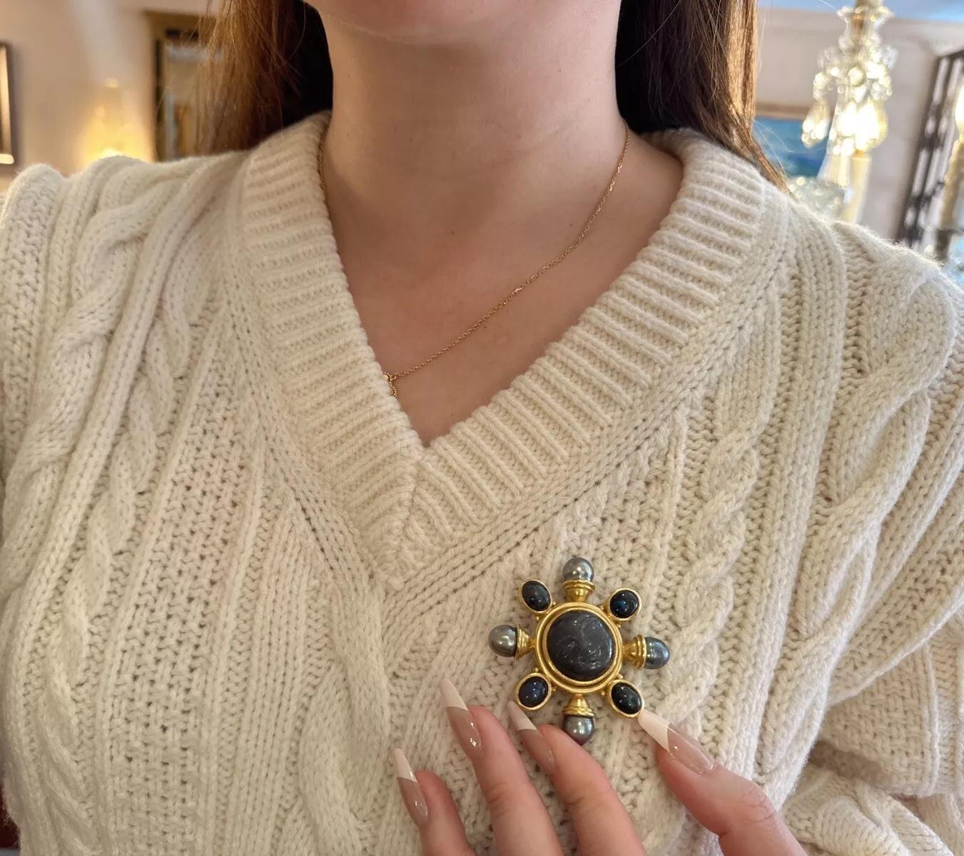 Elizabeth Locke Moonstone, Labradorite, Pearl Brooch and Pendant

Elizabeth Locke Moonstone, Labradorite, and Pearl Brooch/Pendant features a smiling face carved on Grey Moonstone enhanced by a radial of Bezel set Labradorite Cabochons alternating
