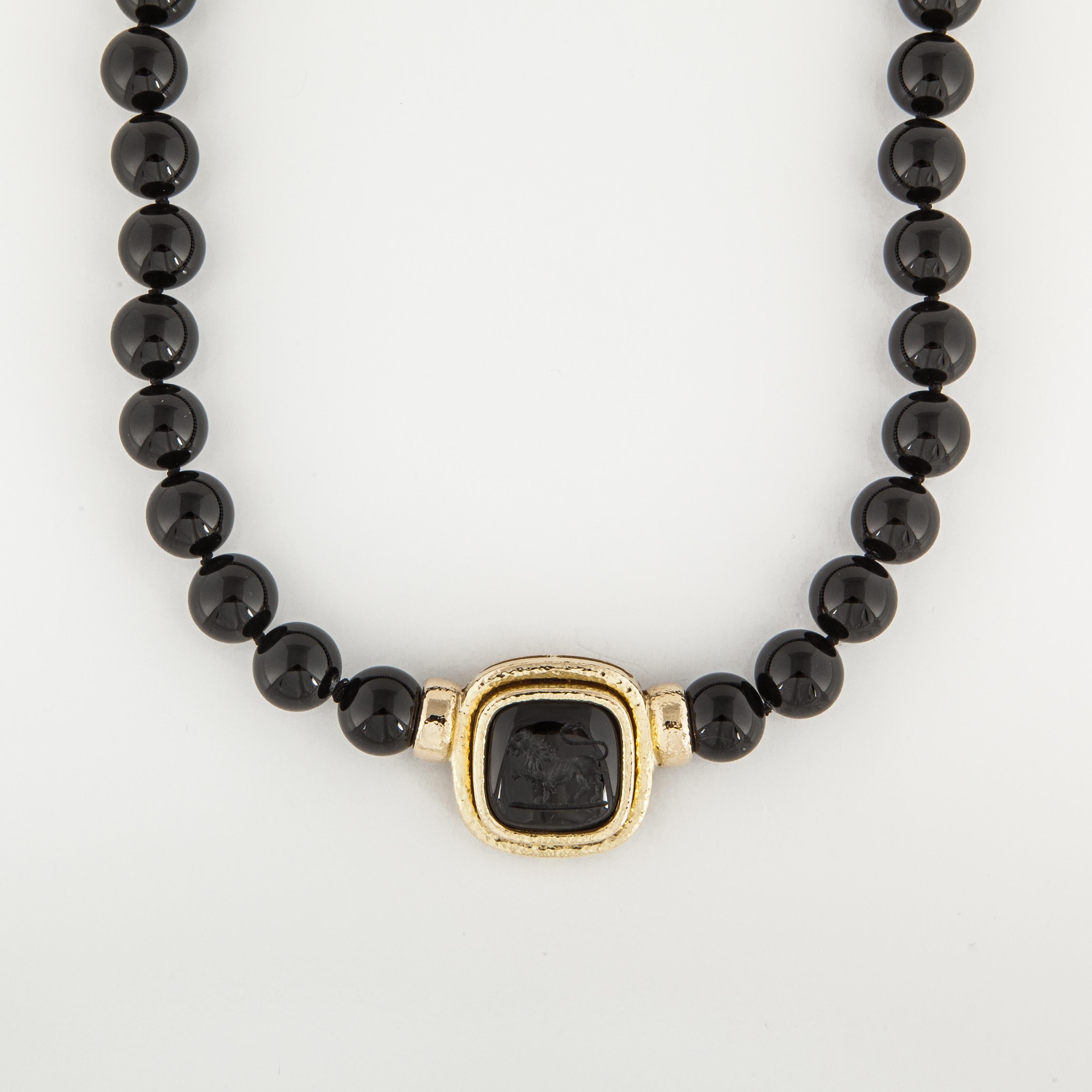 Elizabeth Locke onyx bead necklace with an onyx itaglio in 18K yellow gold.  There are a total of 31 beads measuring 12.0 t0 12.5mm.  Featured centrally on the necklace is an intaglio carved into onyx.  The necklace measures 17 1/4 inches in length