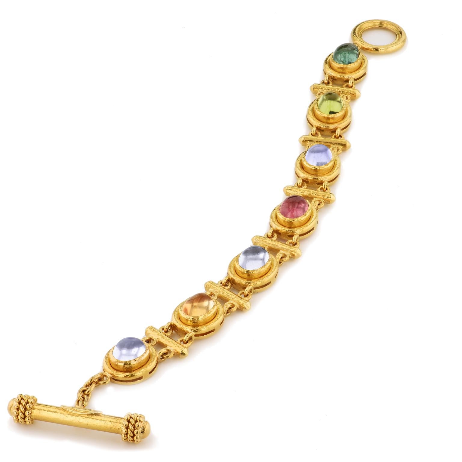 Hammered yellow gold radiates with brazen beauty as seven cabochon moonstone, tourmaline, citrine and peridot illuminate in this previously loved chain-linked Elizabeth Locke 19 karat yellow gold toggle bracelet.