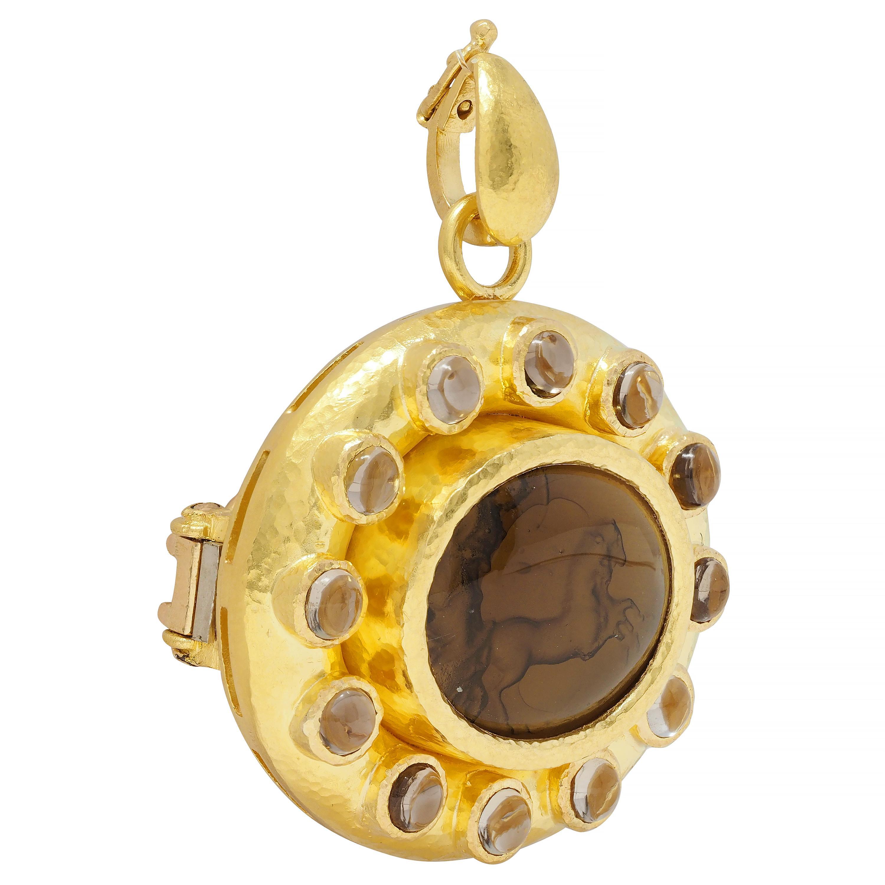 Centering an oval-shaped reverse-carved Venetian glass cabochon measuring 18.5 x 15.5 mm 
Transparent light brown in color - reverse carved with intaglio of a Roman chariot 
With a woman riding in a standing carriage with two horses - bezel set