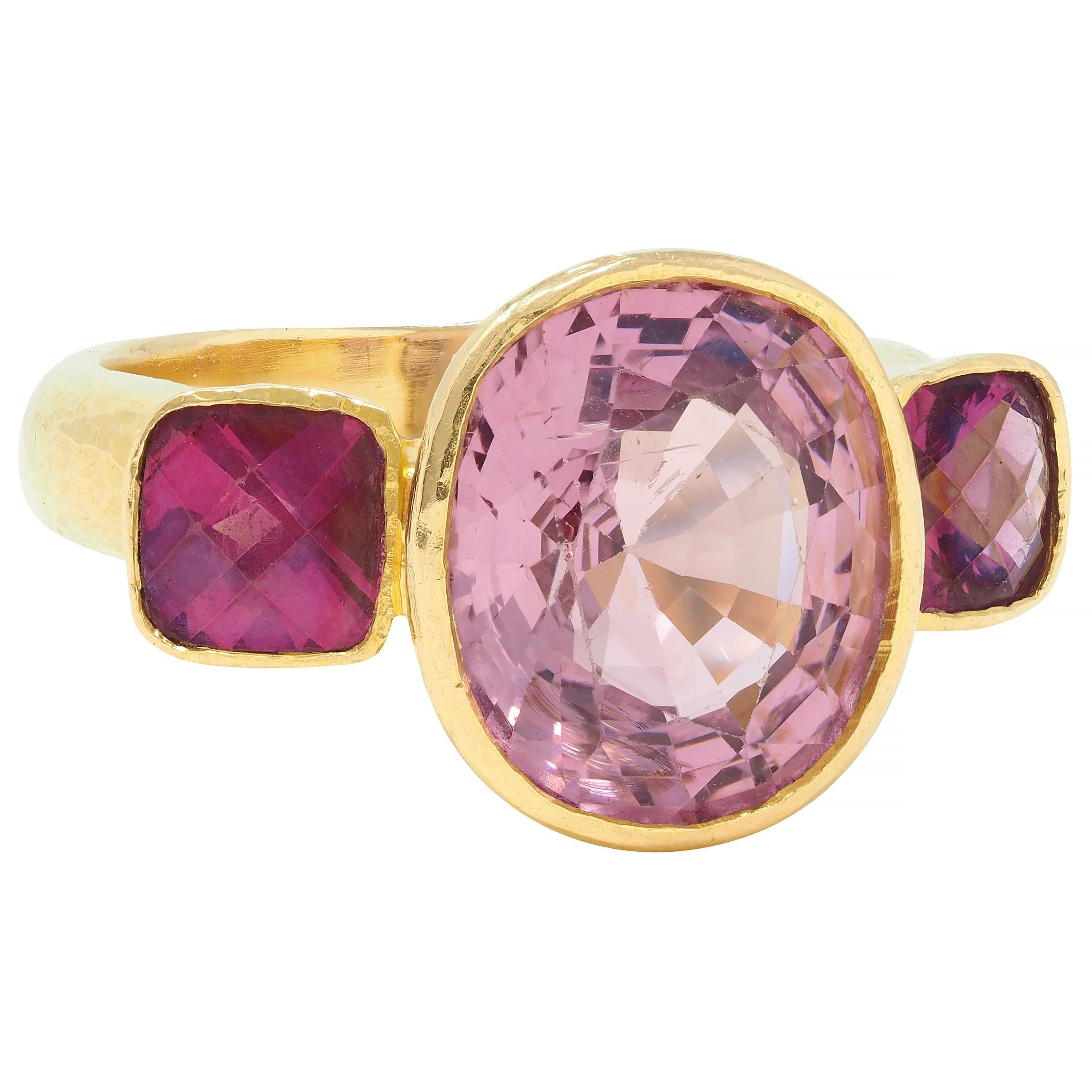 Three stone ring centers a mixed oval cut spinel weighing approximately 4.80 carats
Natural light pink in color and semi-transparent
Flanked by 5.0 mm cushion cut rhodolite garnets 
Well-matched transparent purplish red in color
Each bezel set east