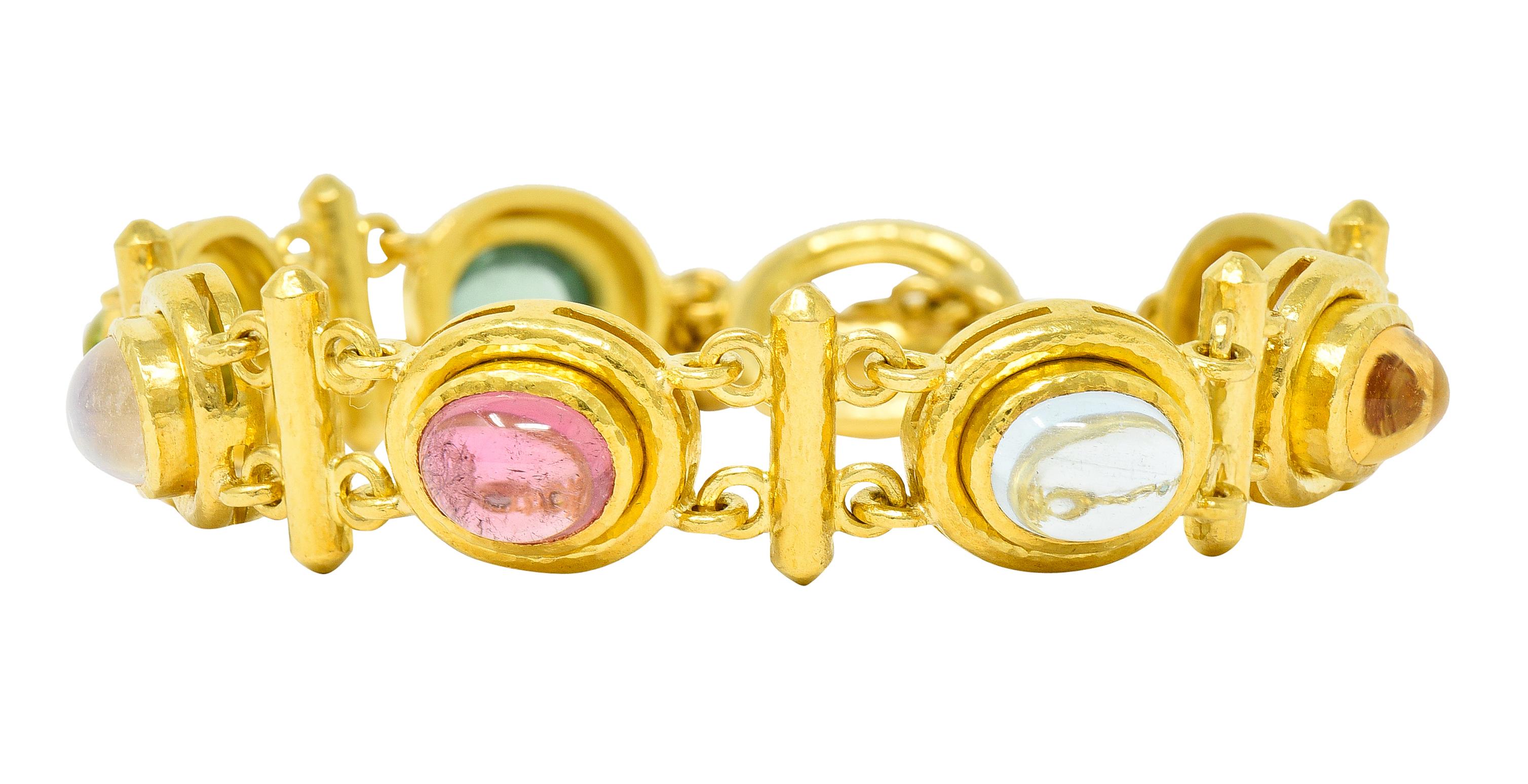 Bracelet is comprised of bezel set links alternating with bar spacer links

Featuring oval cabochons of tourmaline, citrine, moonstone, labradorite, peridot and other

With a hammered gold finish throughout

Completed by a toggle style clasp -