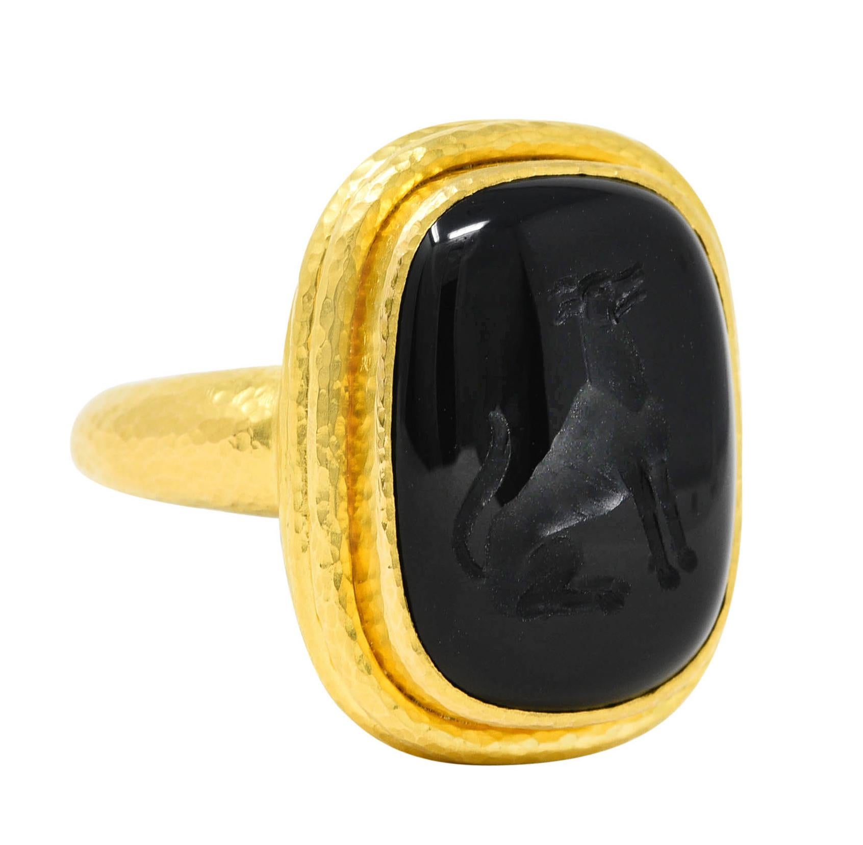 Ring centers a bezel set rectangular cushion shaped onyx cabochon with carved intaglio of a dog

Opaque and deeply saturated black in color - measuring 15.0 x 20.0 mm

With deeply ridged hammered gold surround

Stamped 18k for 18 karat gold

With