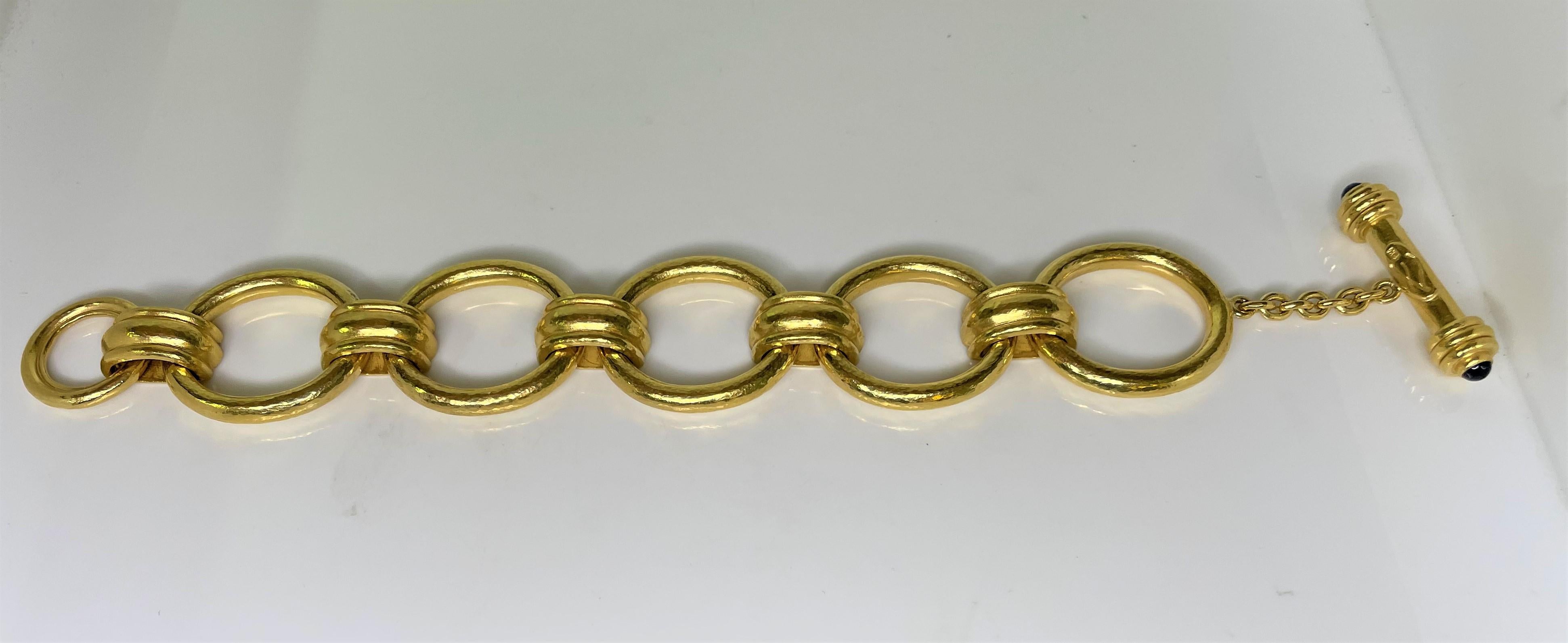 From designer Elizabeth Locke, 19 karat solid hammered style gold link bracelet with toggle.  
Toggle has a cabochon sapphire at each end. 
Stamped with designer trademark.
Bracelet is approximately 7.5 inches long. 
Links are approximately 1 inch