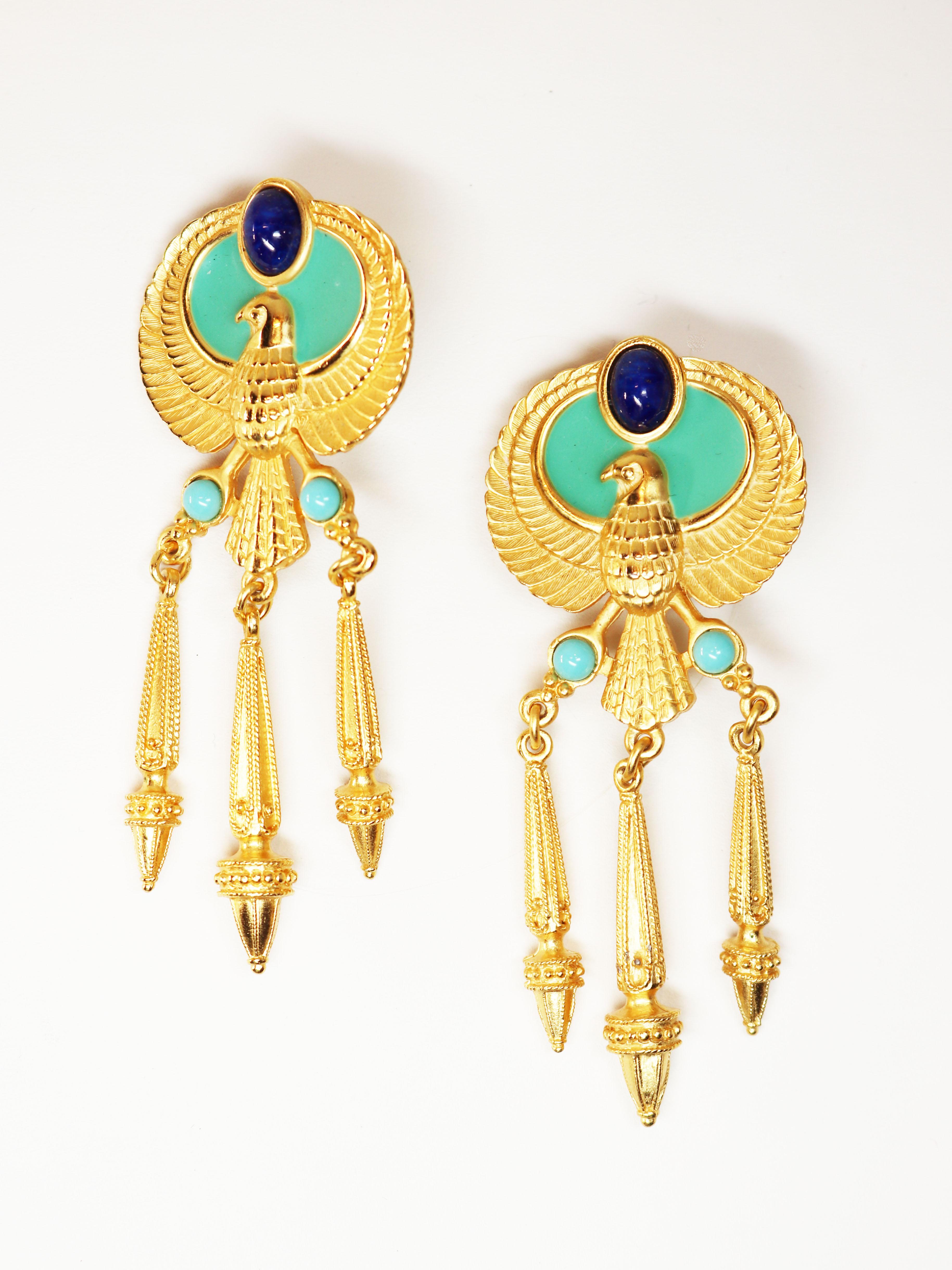 These Elizabeth Taylor “Egyptian Revival” earrings, c. 1993, feature a turquoise base with round, simulated turquoise cabochons and lapis lazuli oval cabochons. Each earring is embellished with three gorgeous, detailed, dangling, geometric drops,